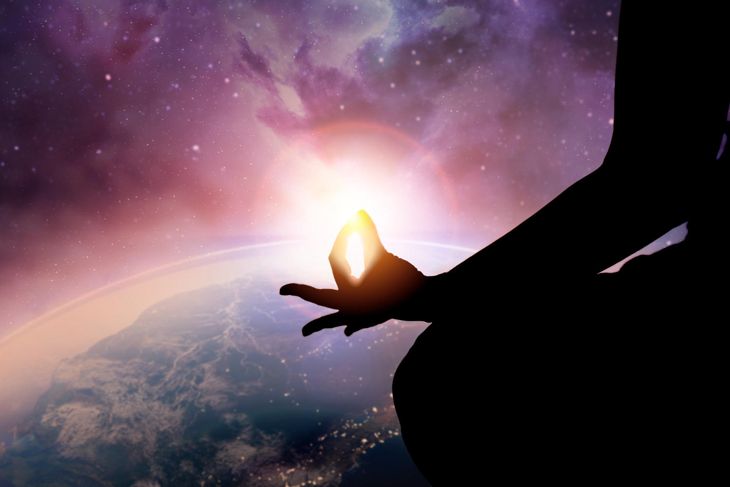 Silhouette of a person meditating with a mudra in front of a view of outer space