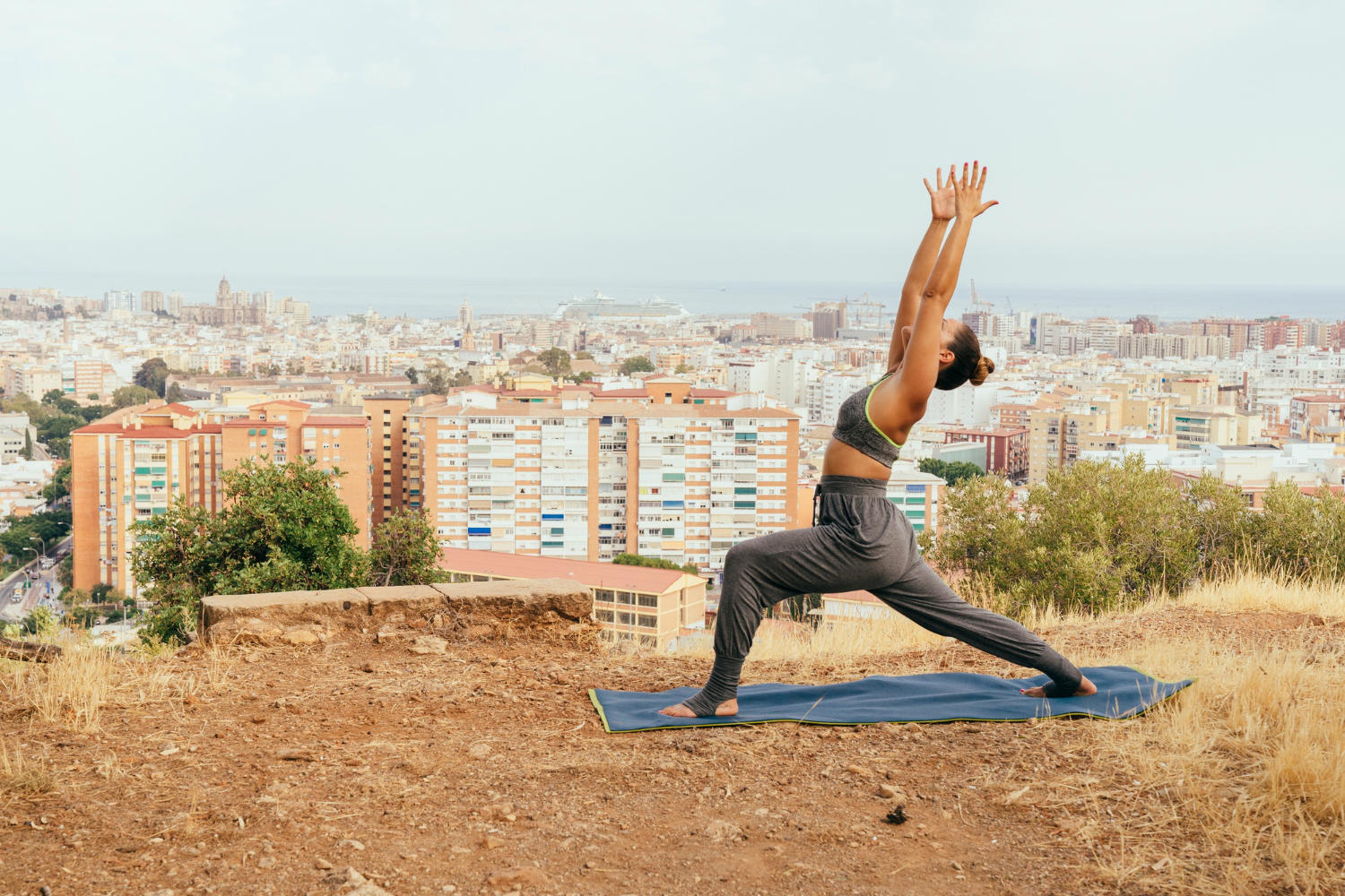 Girl doing yoga with the city far behind her