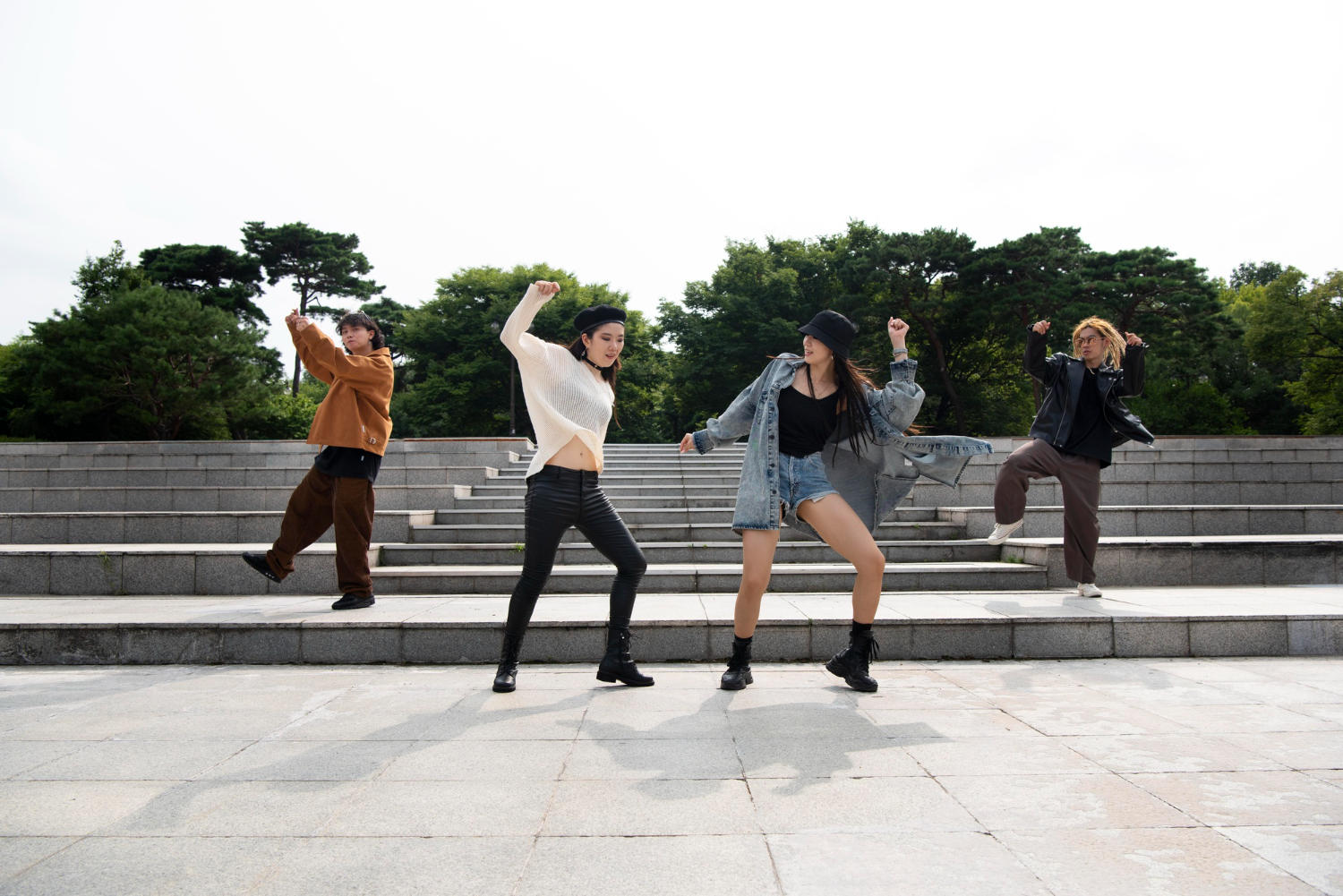 Stylish teens dancing like K-pop groups in a park
