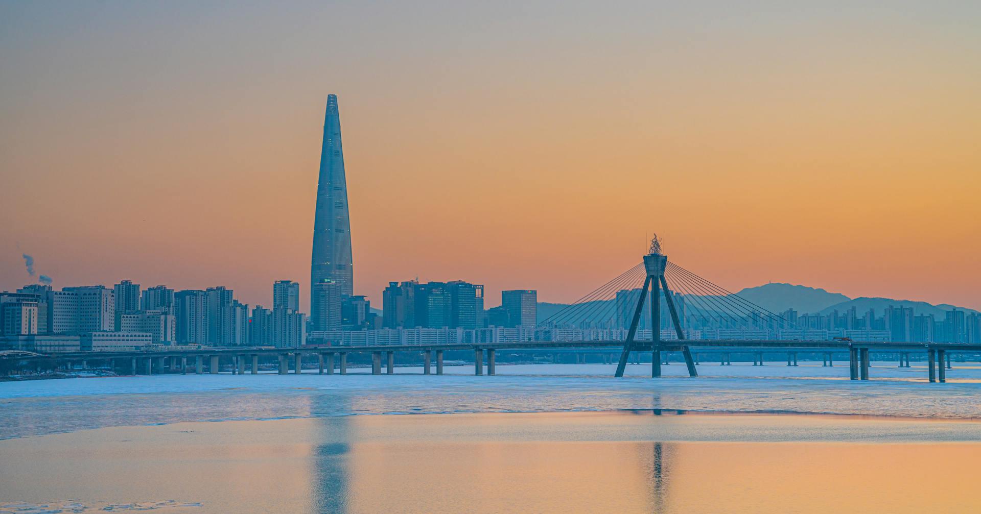 The Seoul city skyline at sunrise with a yellow sky and blue cityscape