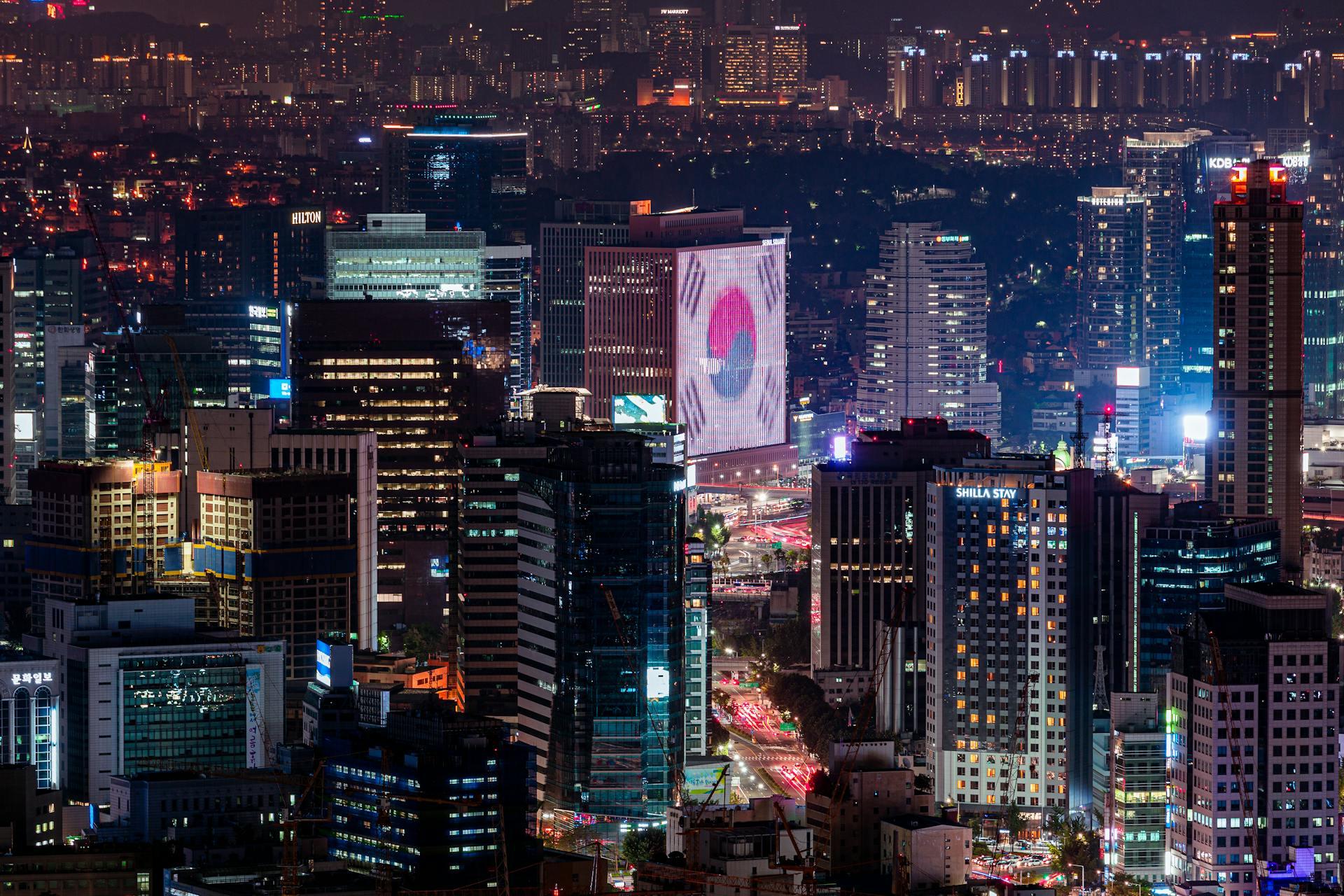 City of Seoul at night with a South Korean flag projected on a skyscraper