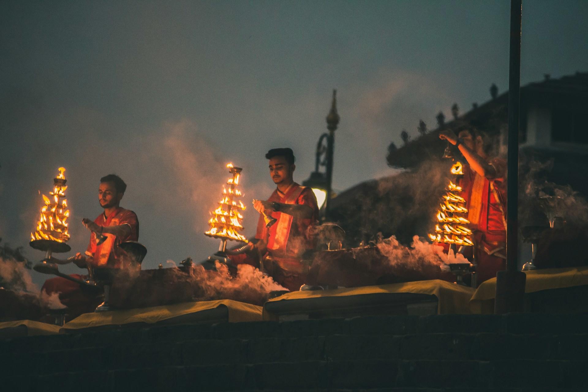 People in religious garb performing a fire ritual near the Ganges River.