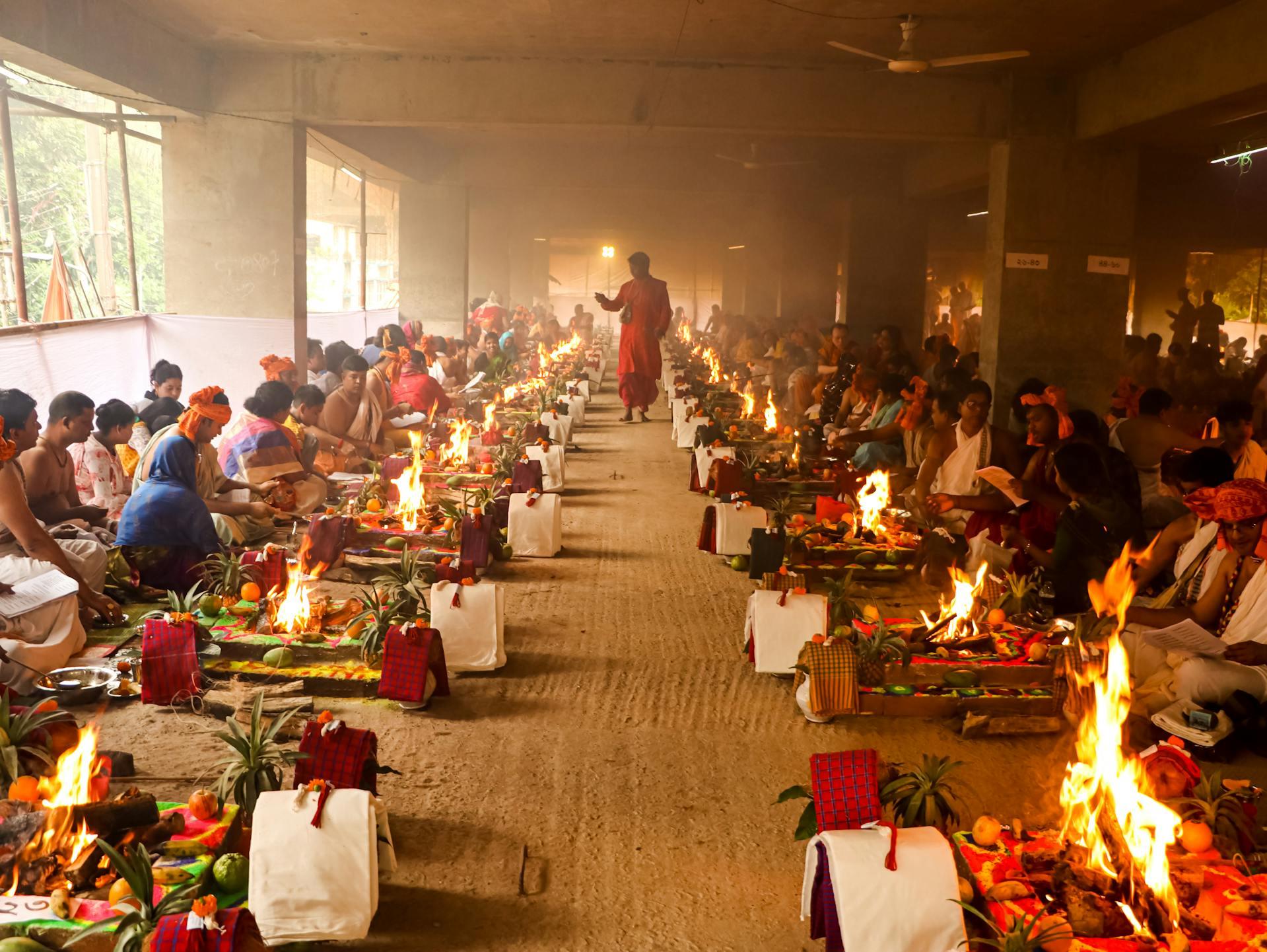 A large hall where many people are performing puja at separate altars.