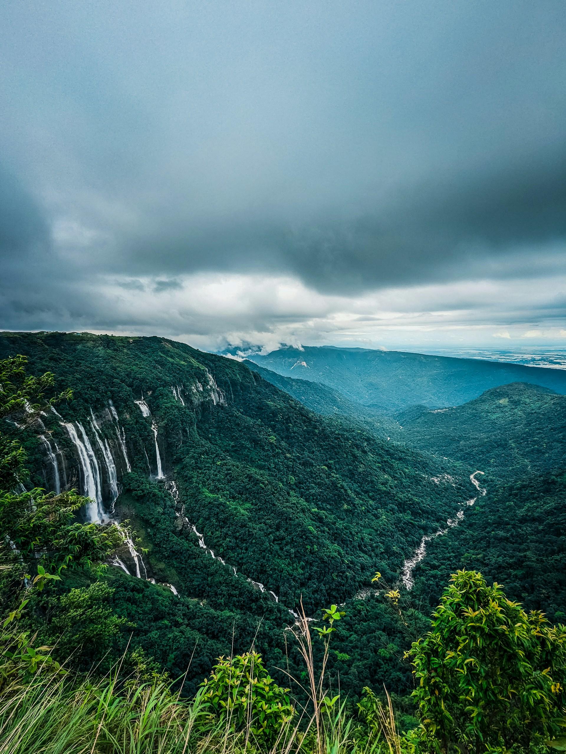 A landscape view overlooking a forested valley with waterfall in Cherrapunji