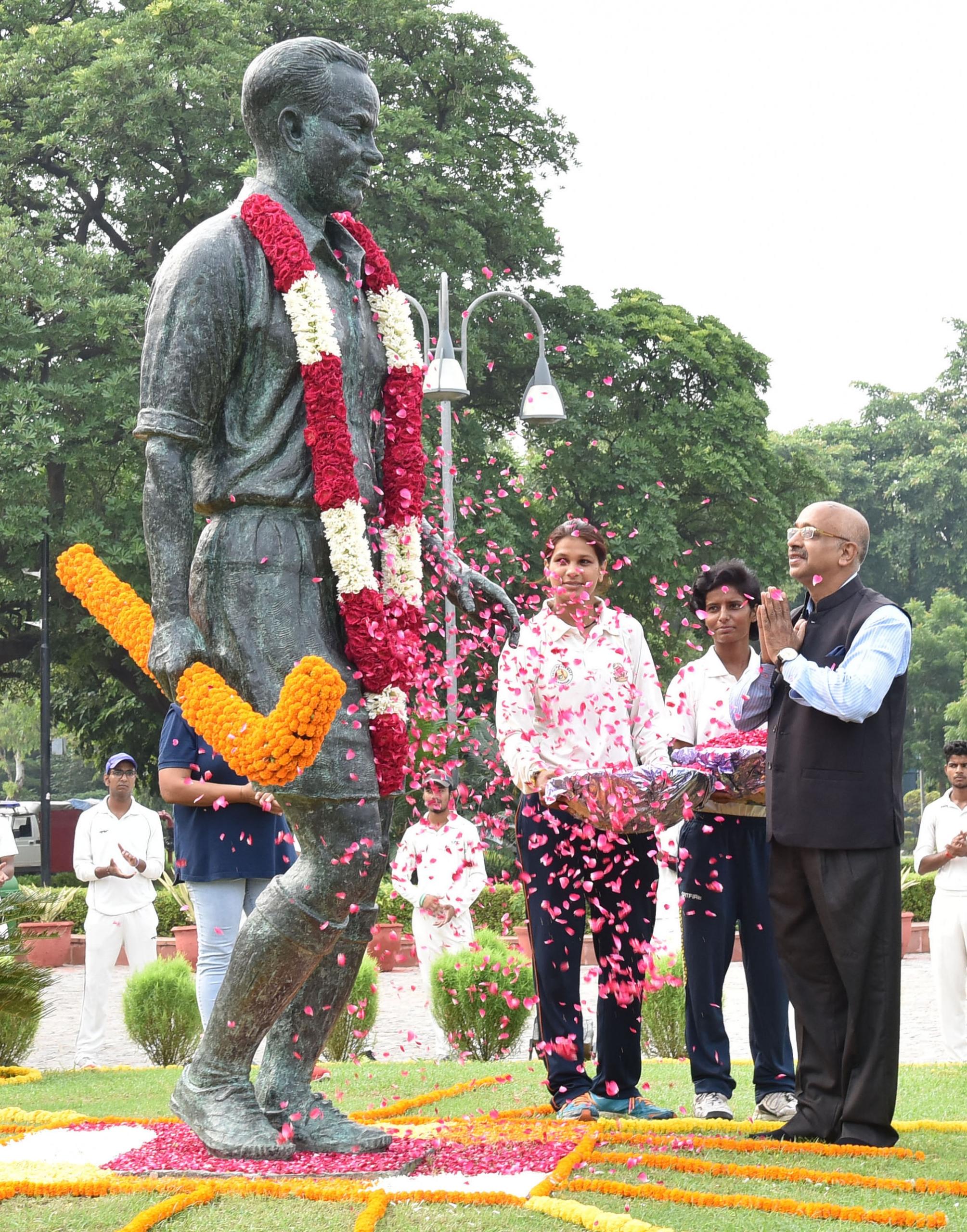 A statue of Major Dhyan Chand with ceremonial flowers