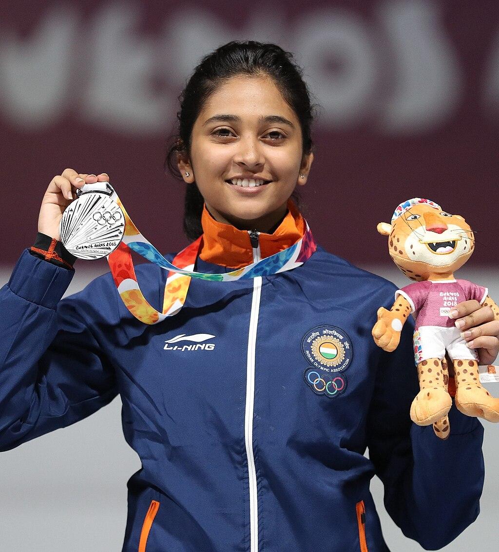 Mehuli Ghosh holding up her winning medal and stuffed animal mascot of the games