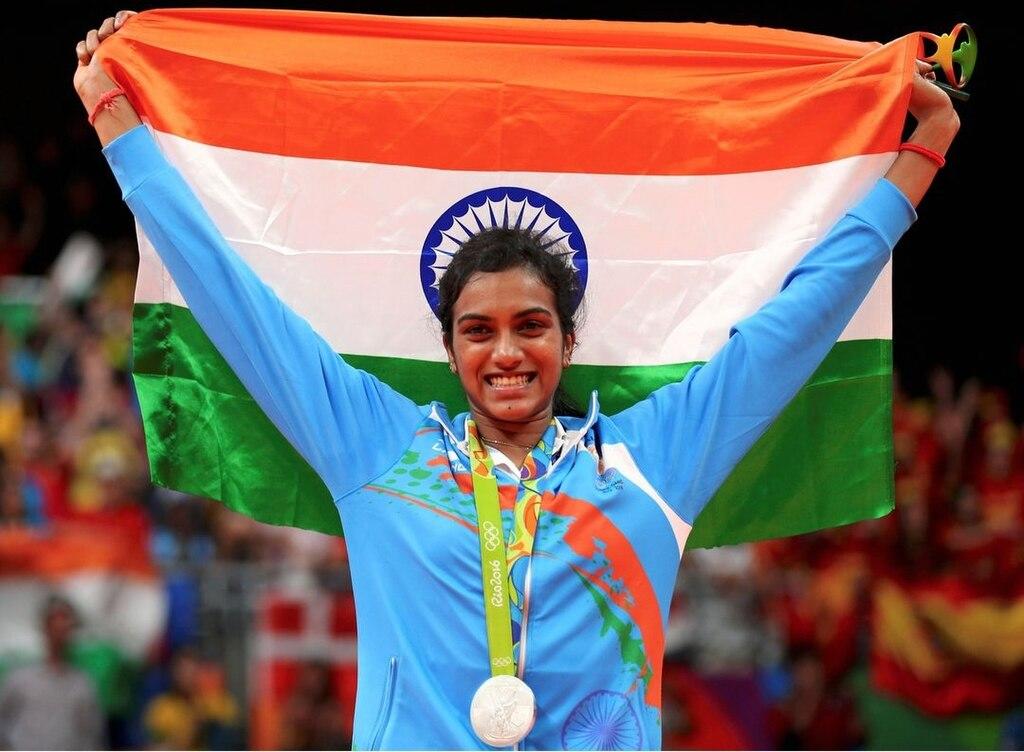 PV Sindhu holds up the Indian flag behind her head as she wears the silver medal