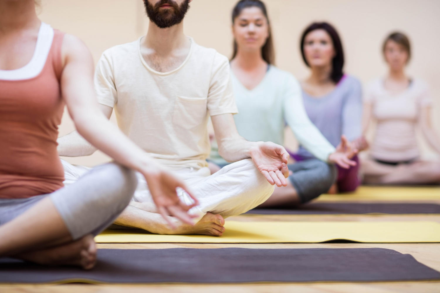 a class of students in lotus pose meditating with a hand mura