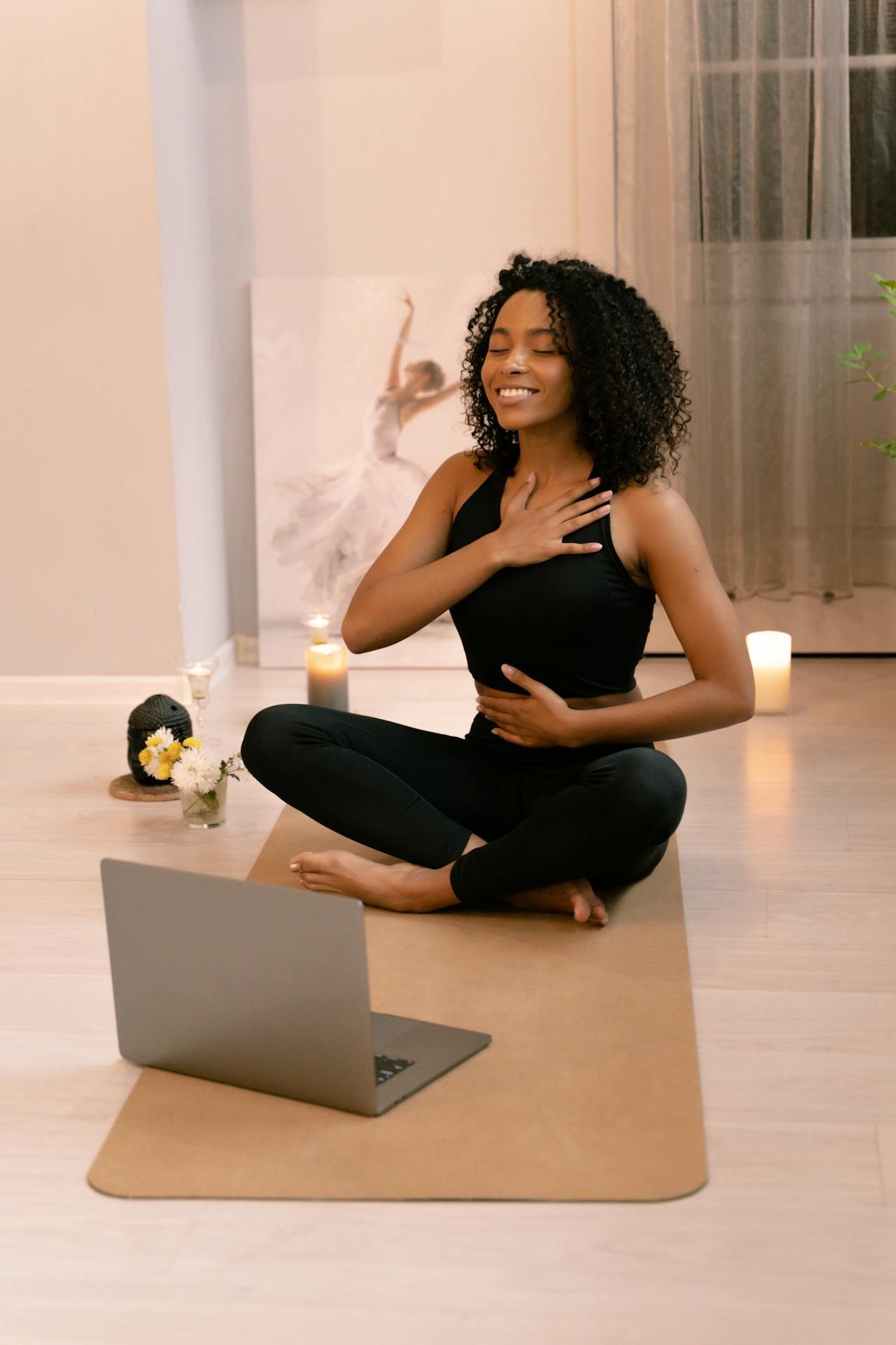 A yoga teacher leading an online class from her yoga mat