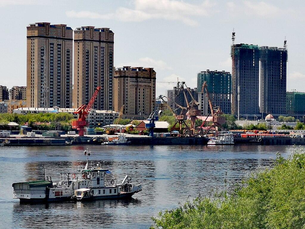 The Amur River flowing by a city with cargo boats