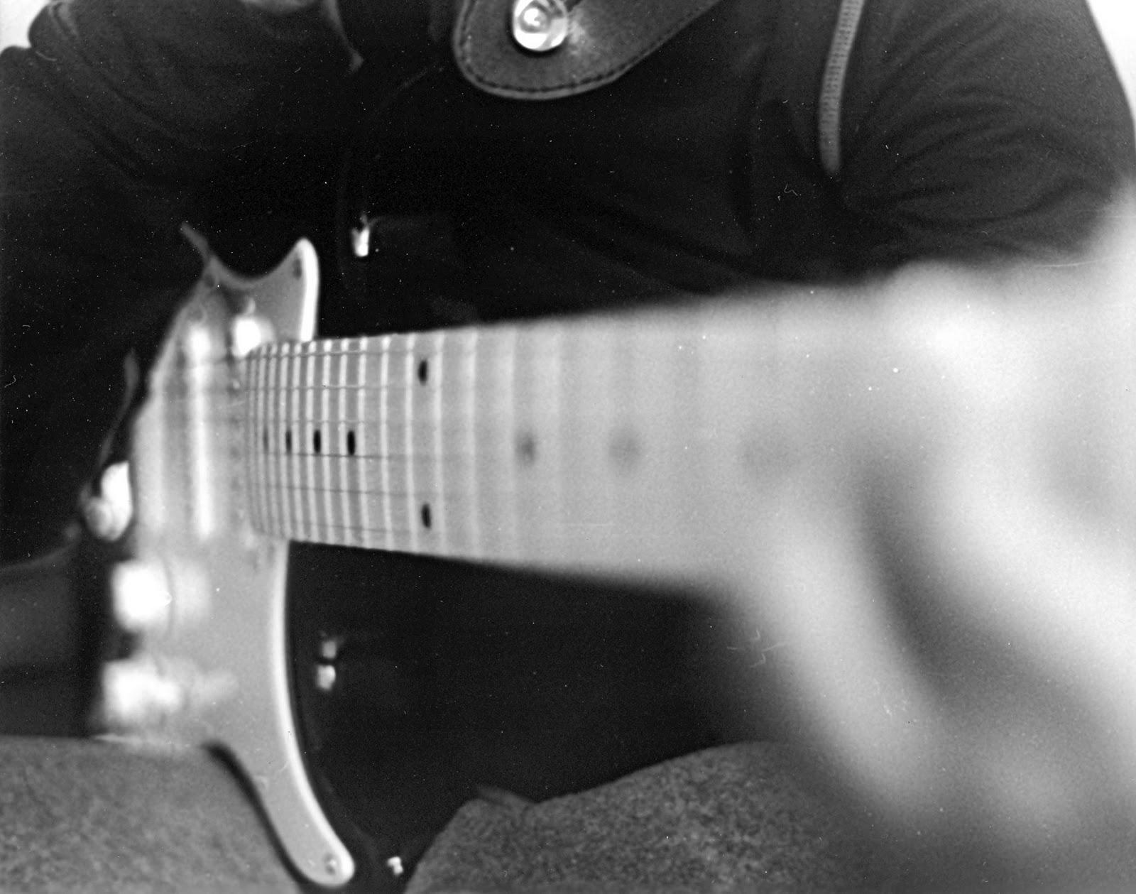 The neck and body of a guitar, with someone playing it