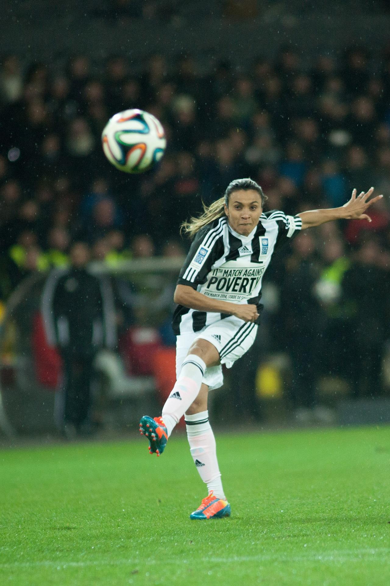 A woman kicks a soccer ball on a football pitch