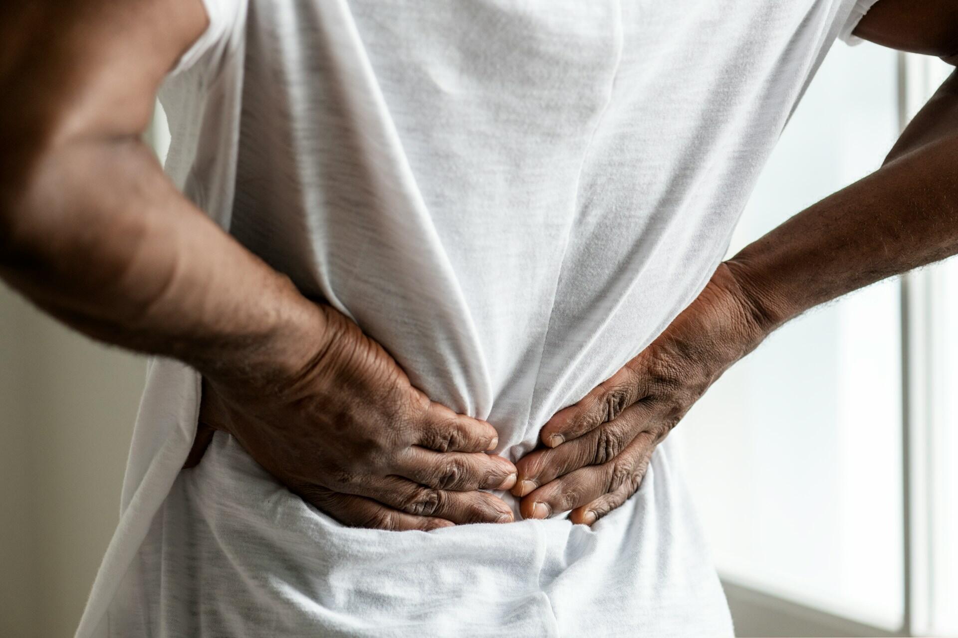 Ragazzo si massaggia la schiena dolorante: per questo problema è importante rafforzare i muscoli addominali