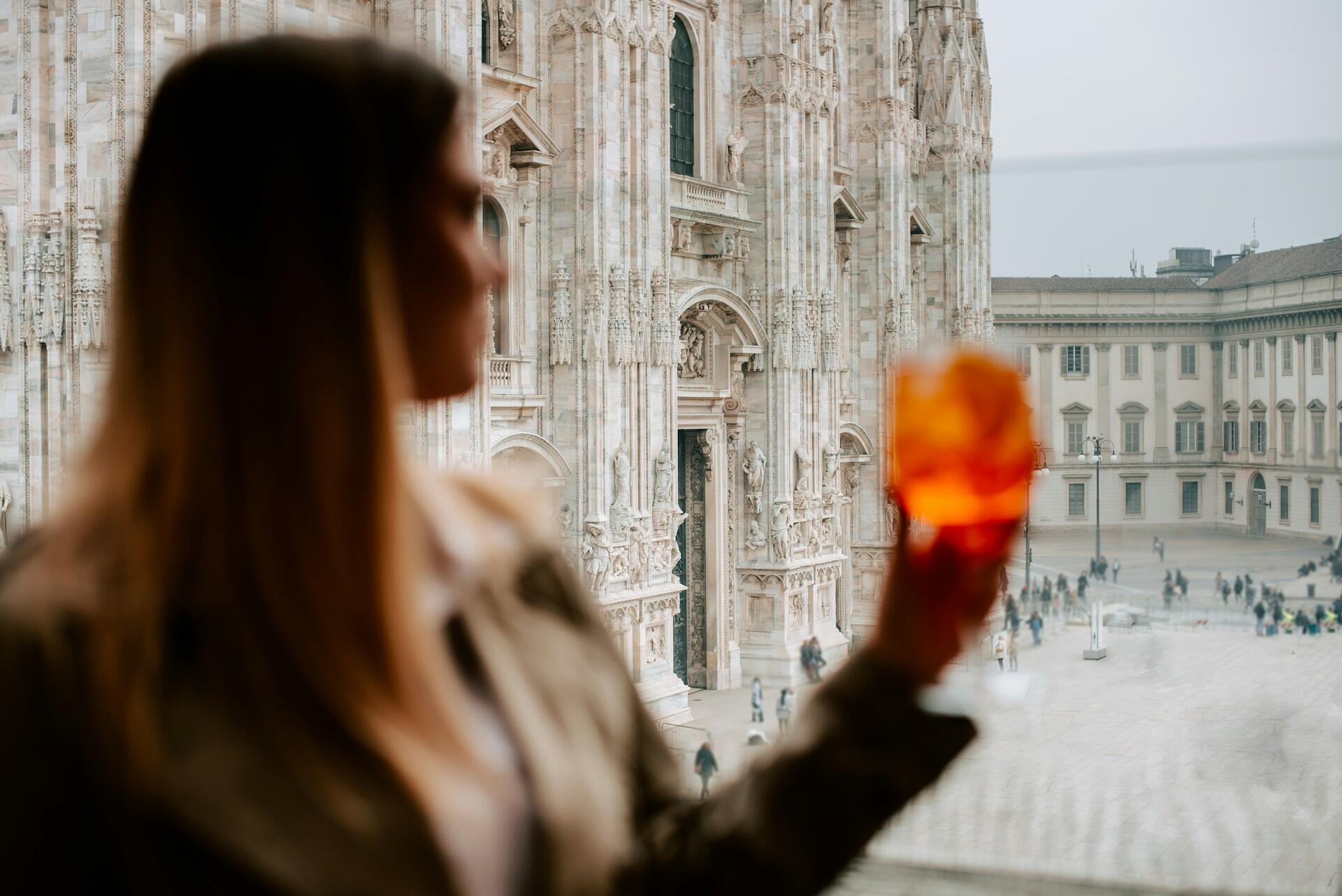 Una ragazza beve uno spritz davanti al Duomo di Milano.