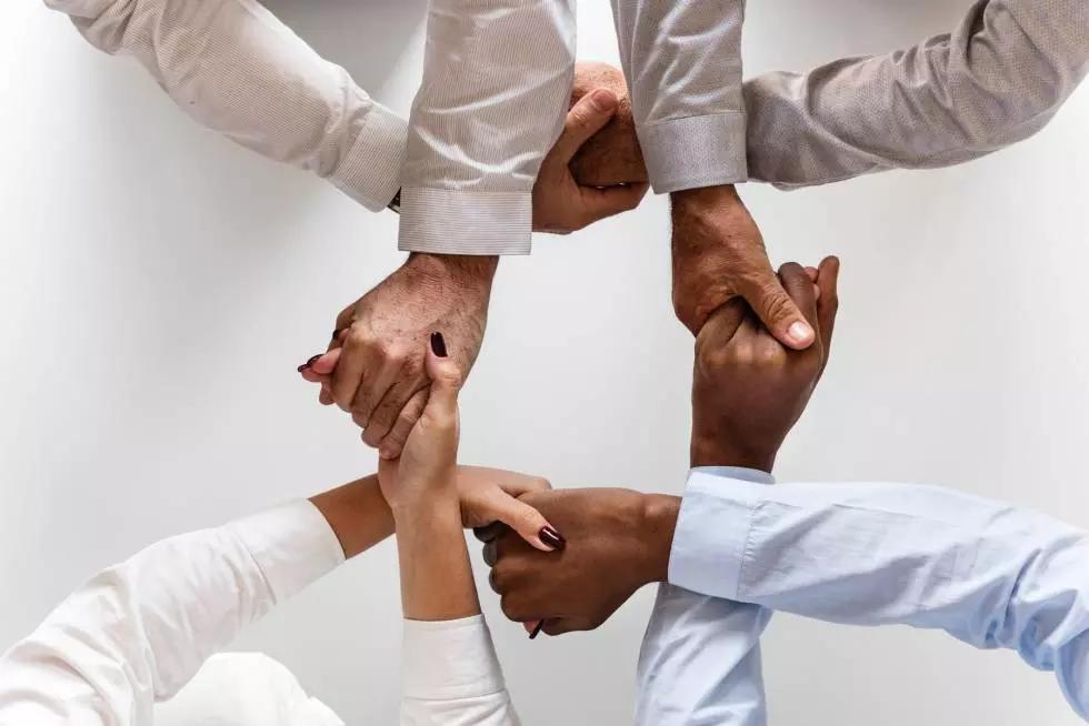 Stare insieme, incontrarsi: quattro persone si stringono la mano formano uno zero e, tuttavia, è l'unità che simboleggiano!
