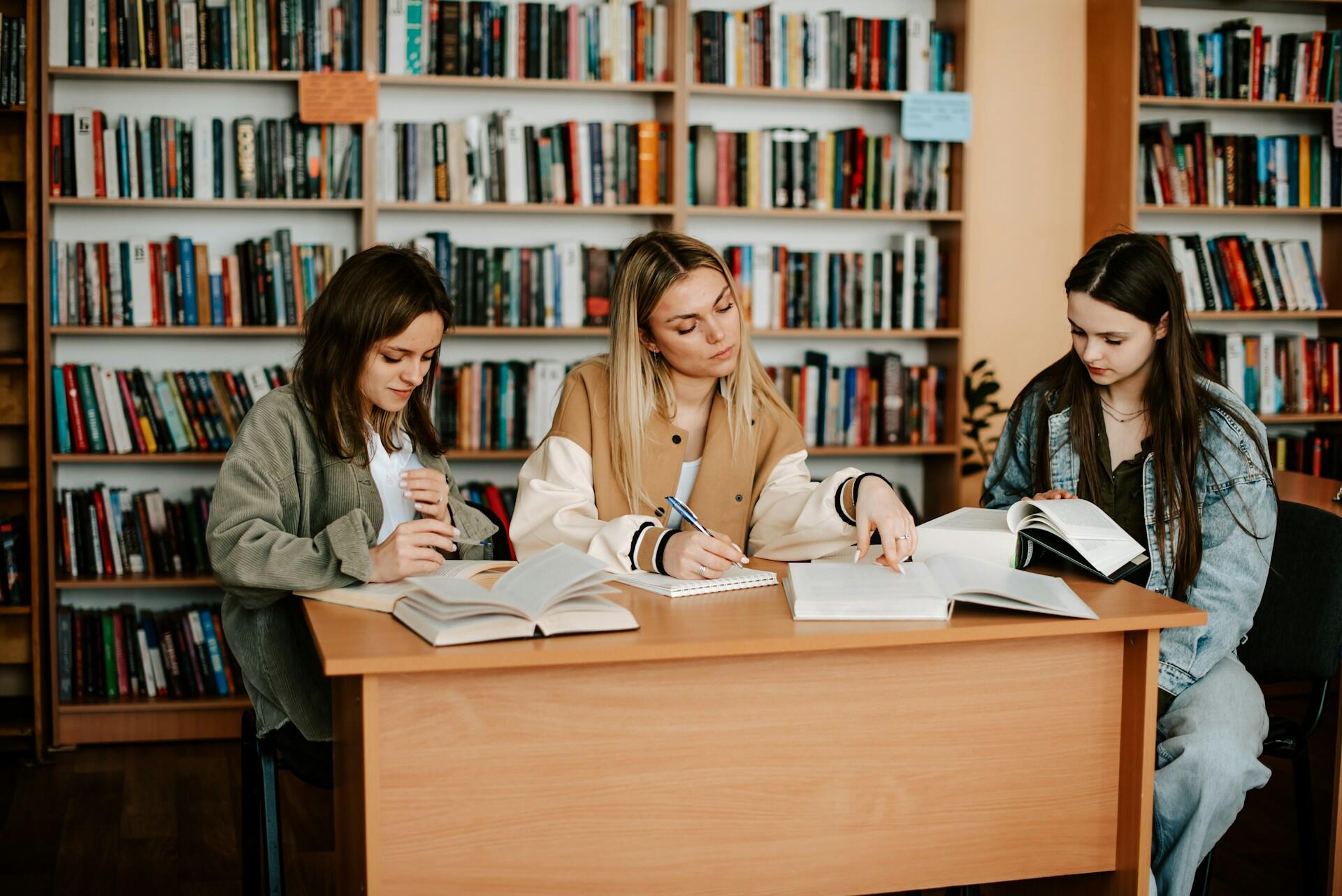 Tre ragazze si preparano al TOEIC in una biblioteca. 