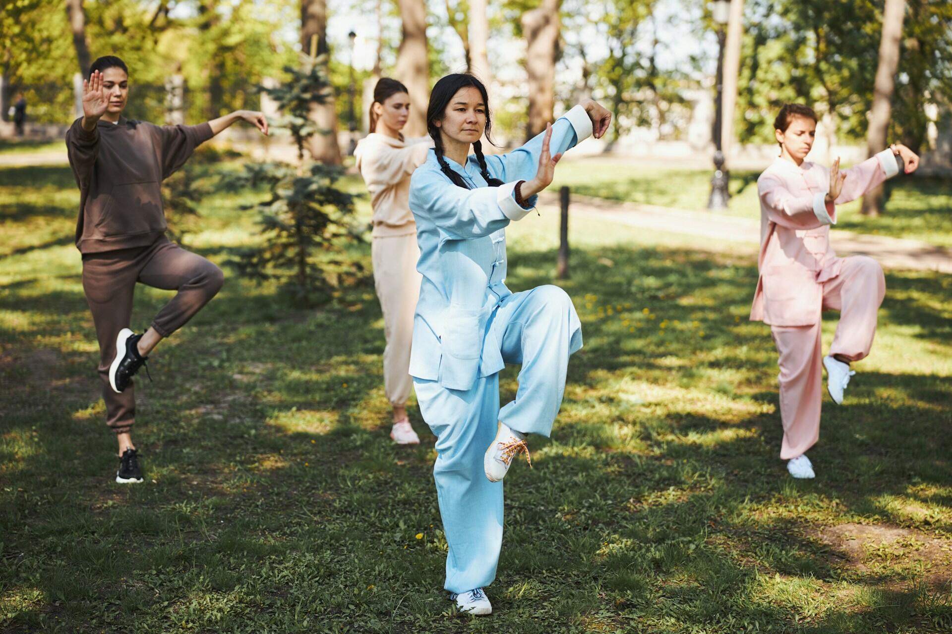 Ragazze praticano pose di Tai Chi in un parco.