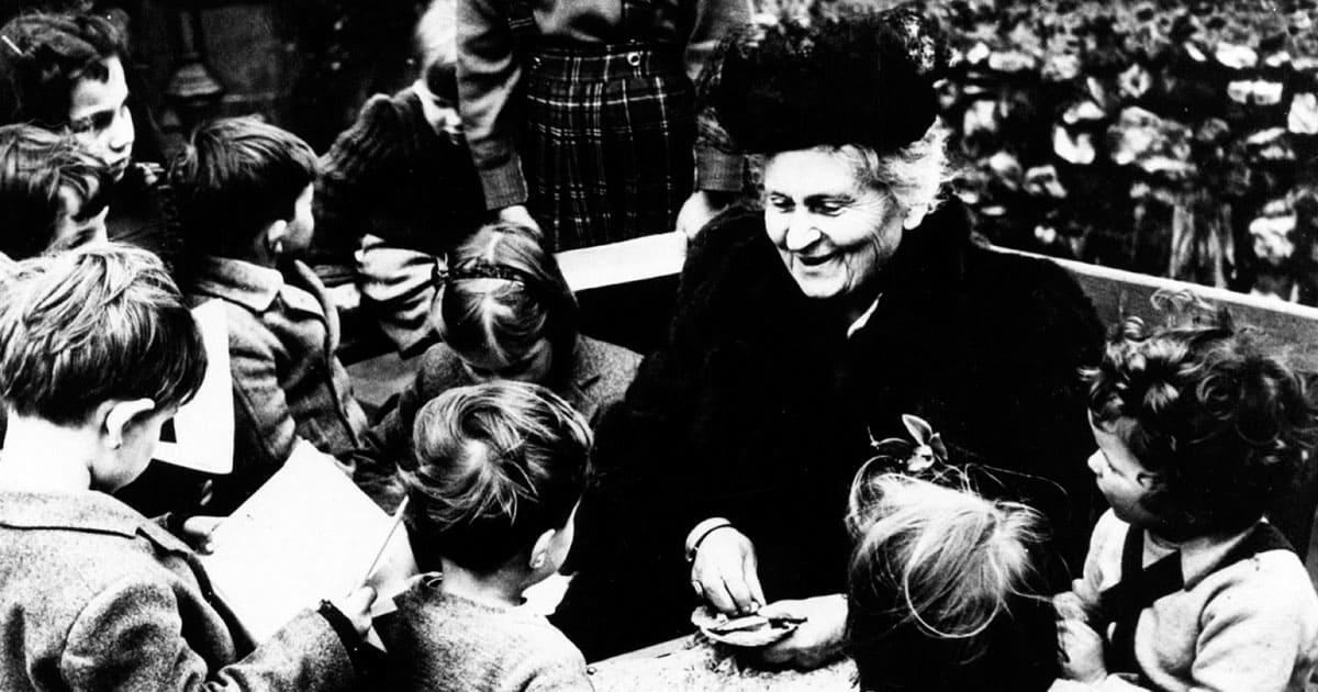 Foto in bianco e nero di Maria Montessori circondata da bambini.