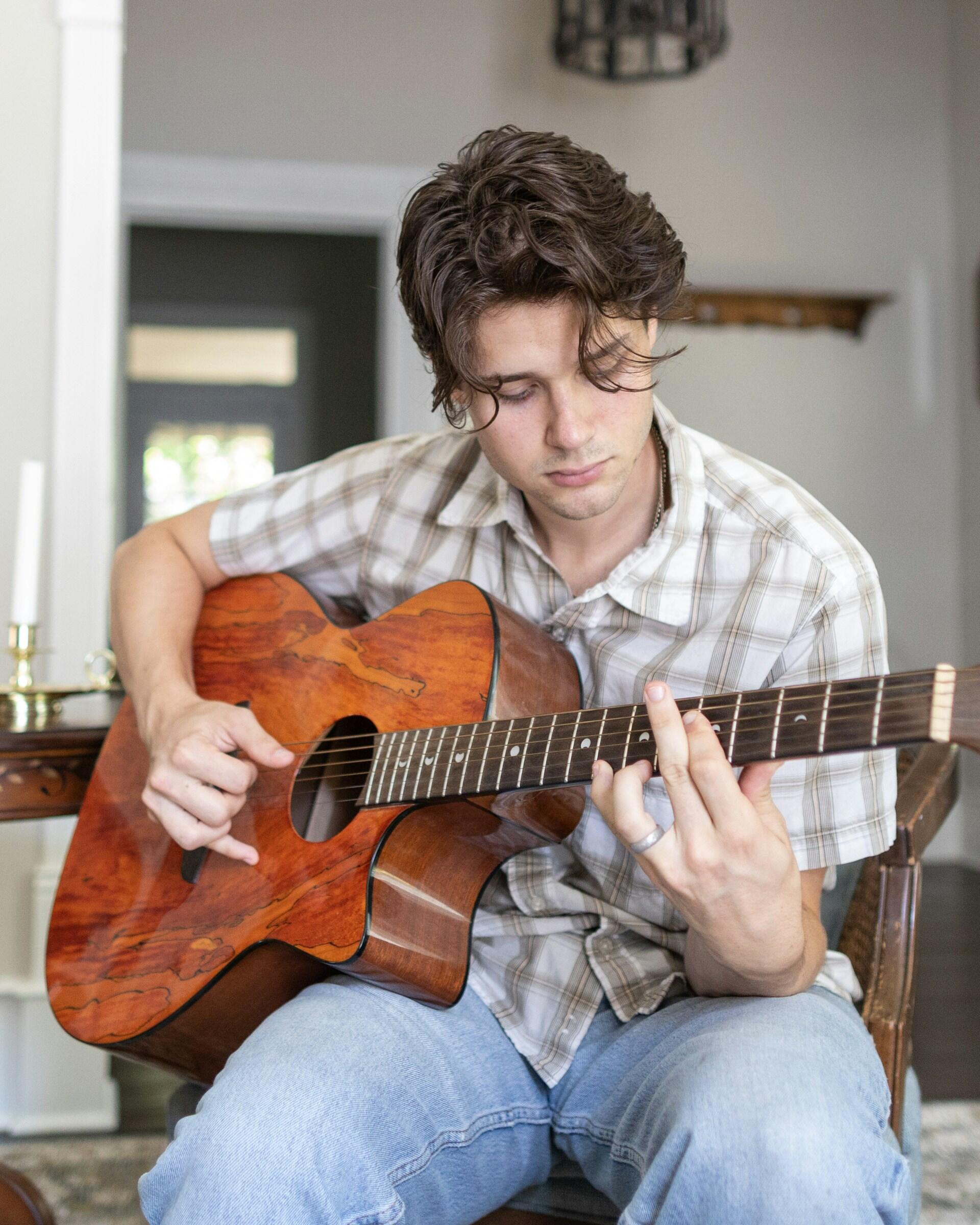 Un giovane ragazzo si esercita a suonare gli accordi alla chitarra.