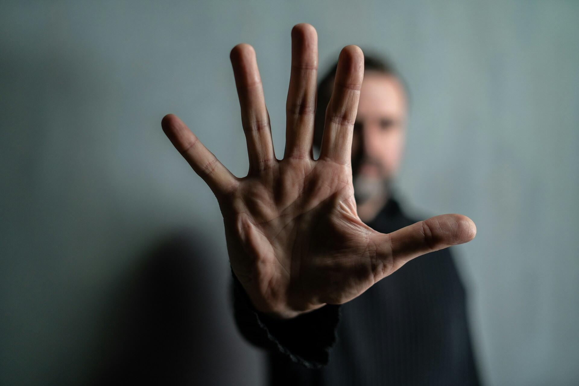 Un uomo tiene il palmo della mano aperto per dire "stop". 