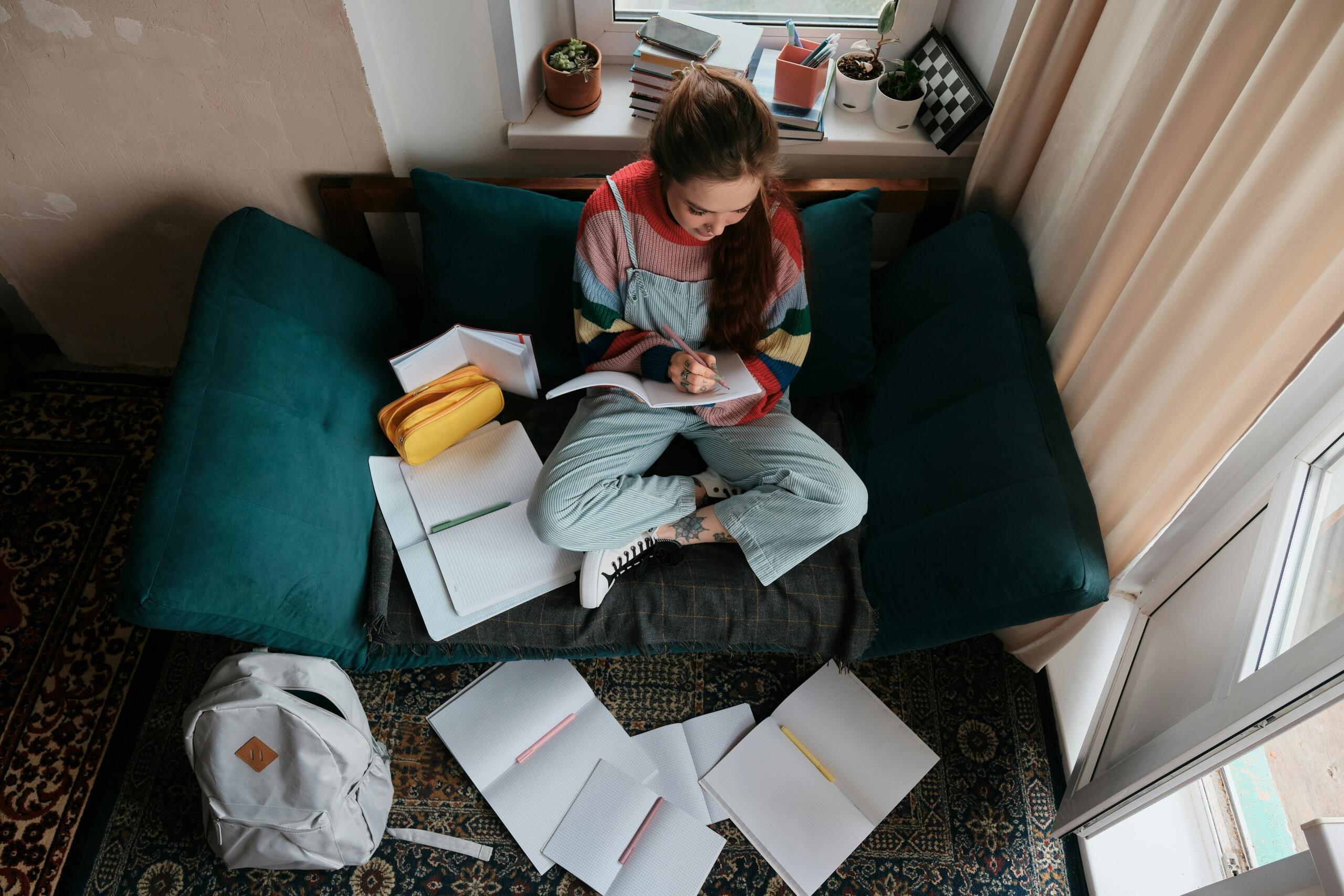 Ragazza seduta sul divano scrive sul quaderno.