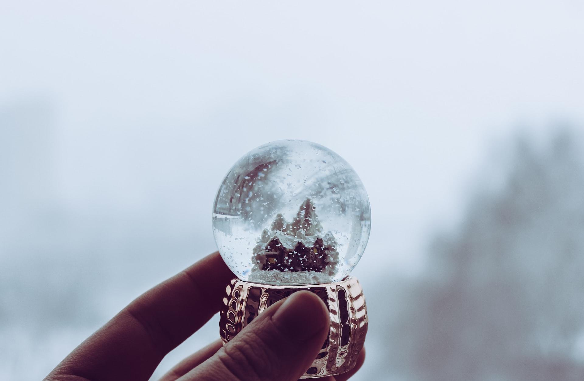 Mano che regge sfera con neve