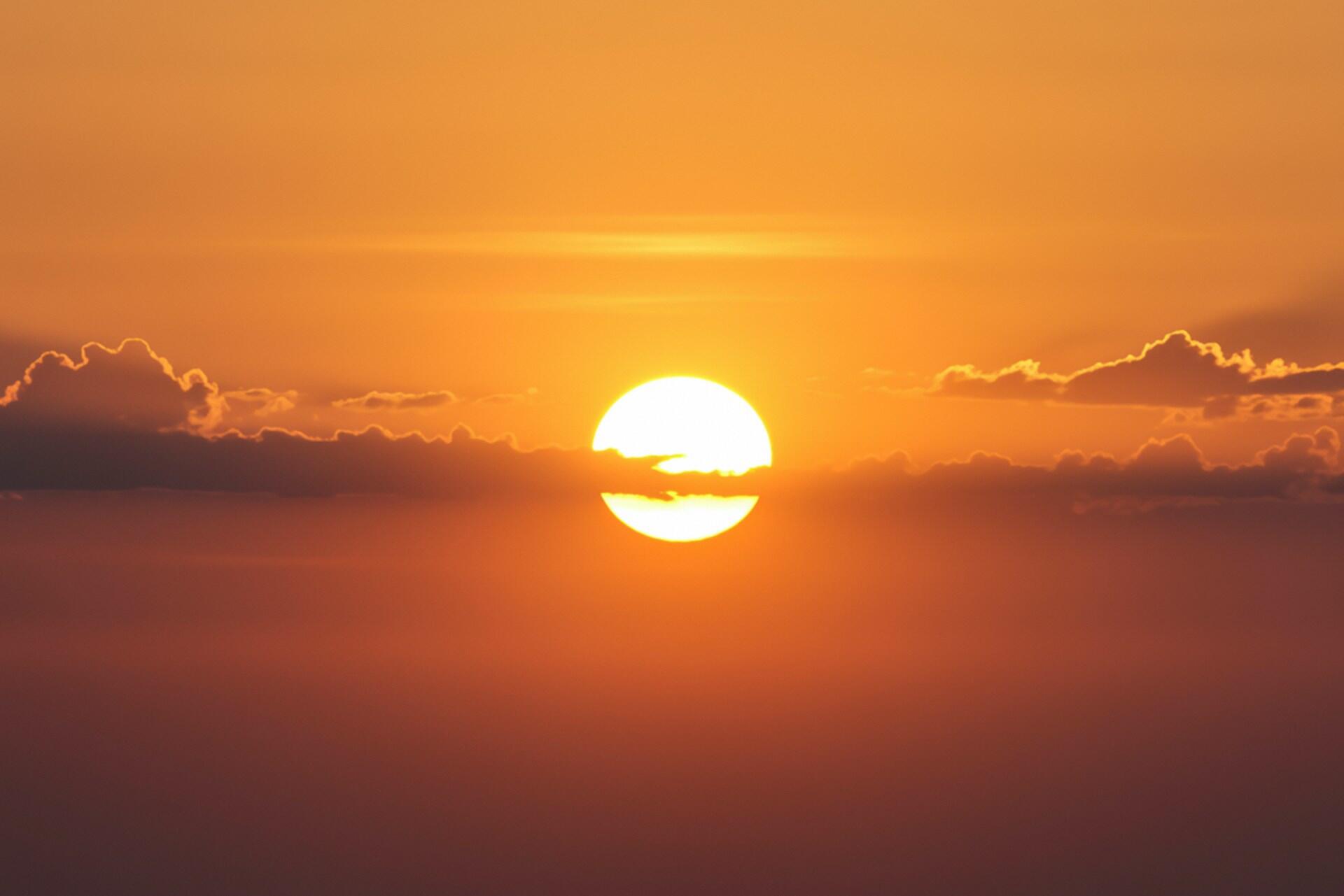 Il sole al tramonto con qualche nuvola.
