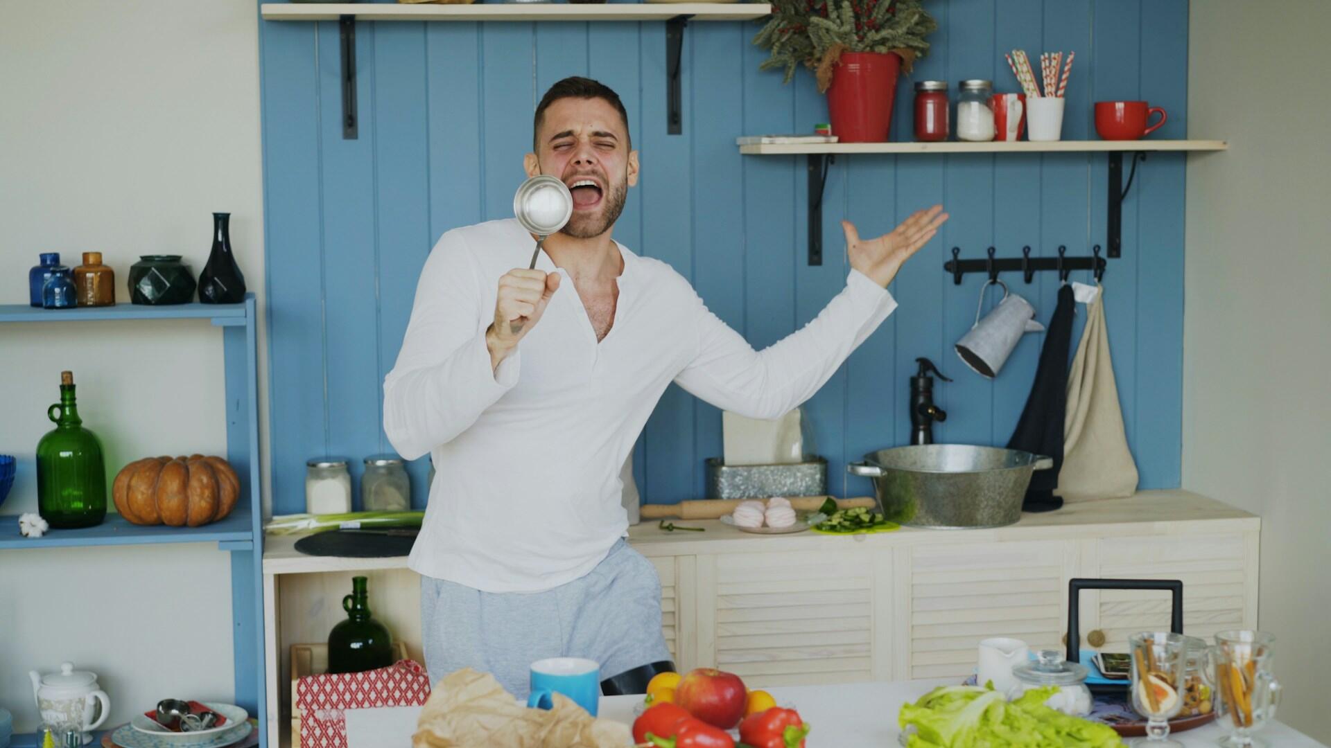 Un uomo si diverte fingendosi un cantante e usando un mestolo come microfono.