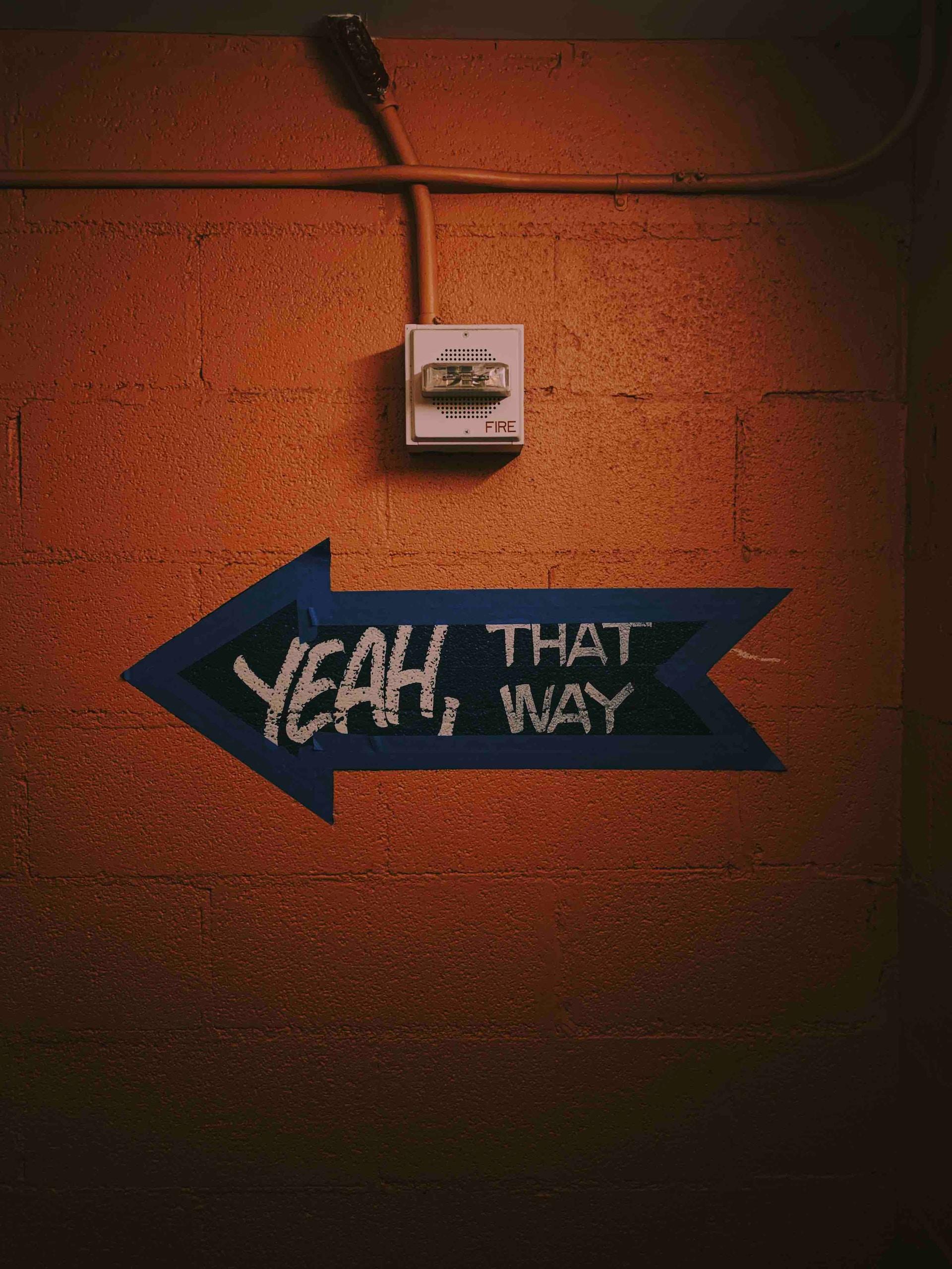 Freccia sul muro con scritta "yeah, that way"