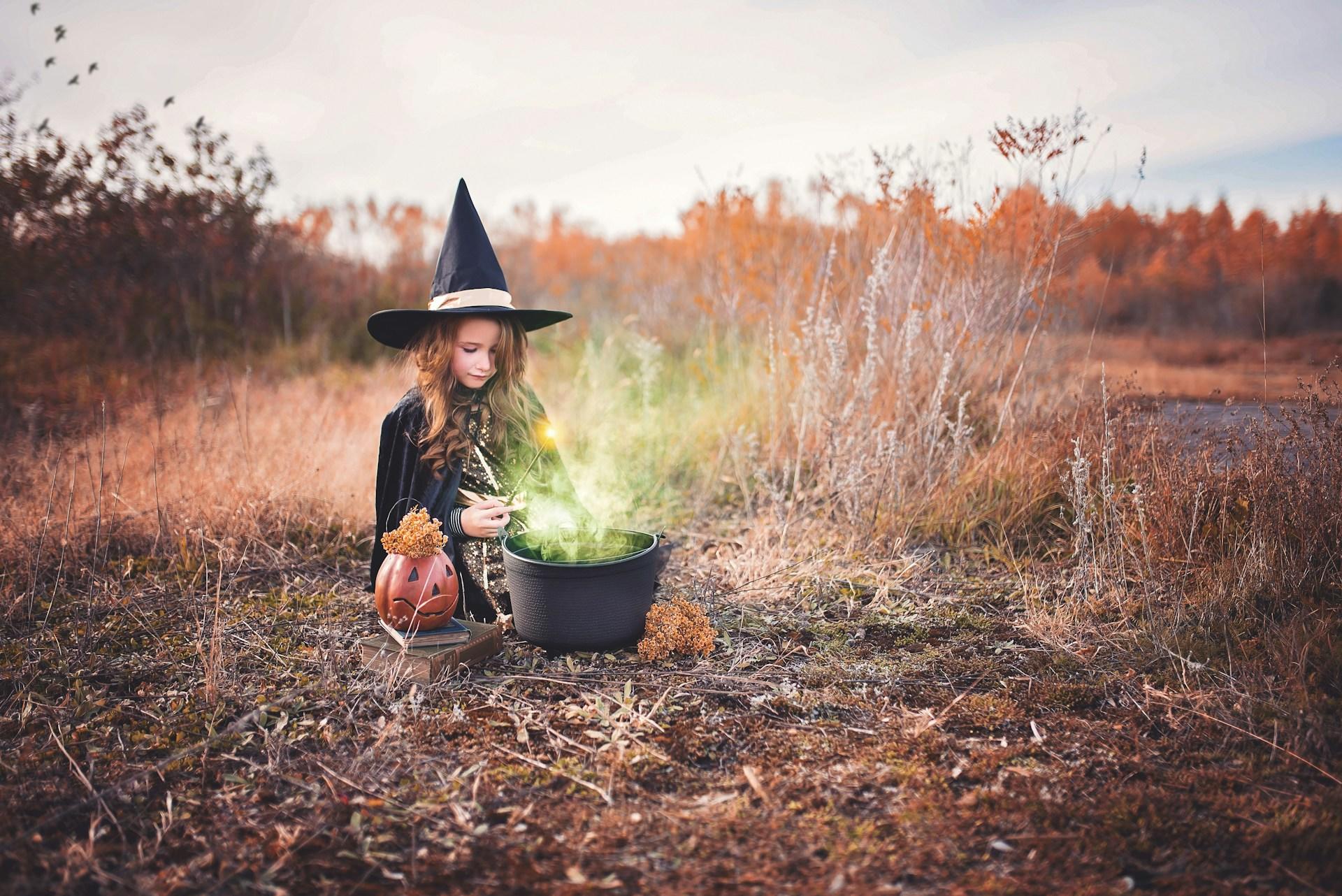 Bambina con costume di Halloween da strega e pentolone