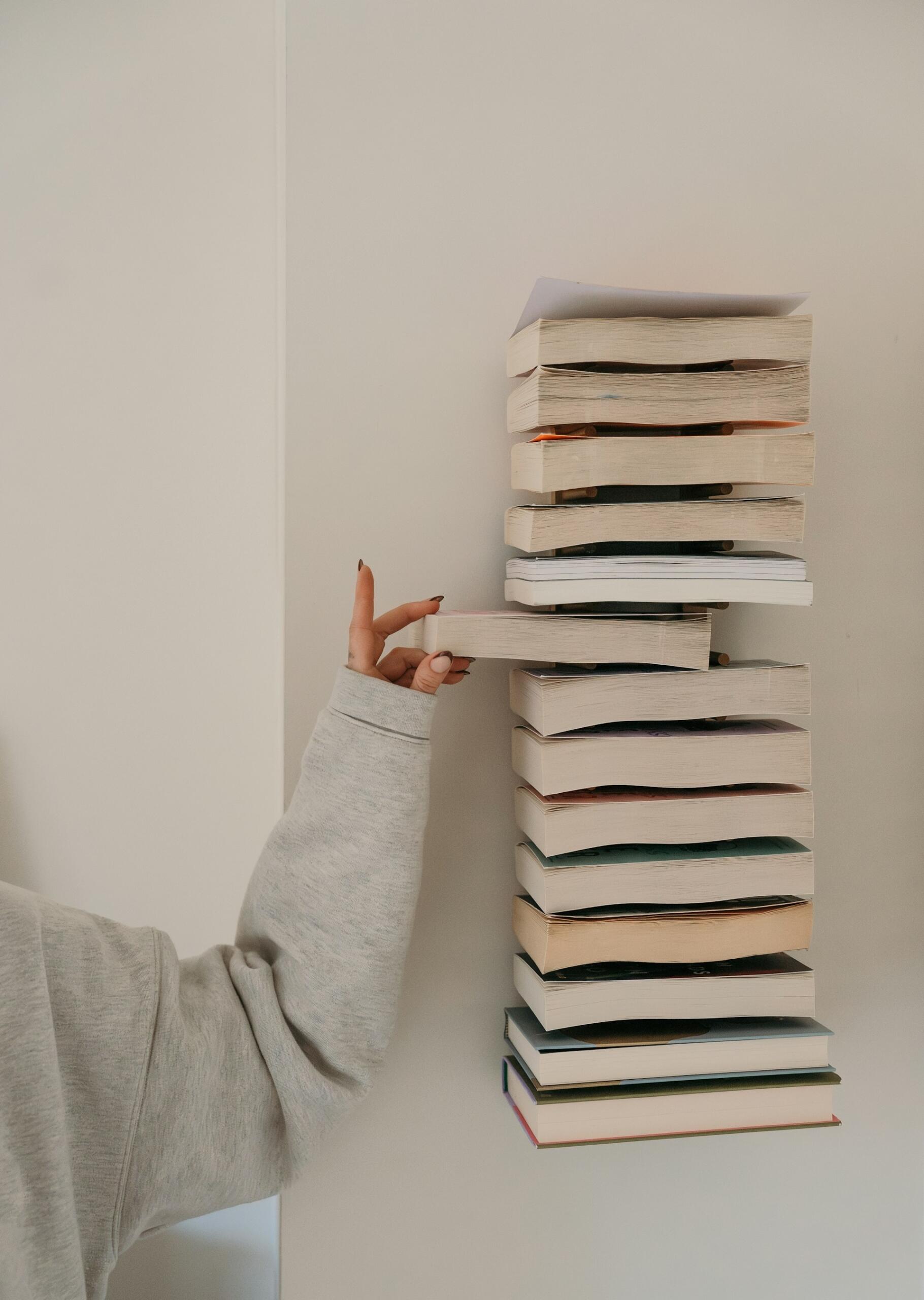 Ragazza pesca un libro da una pila.