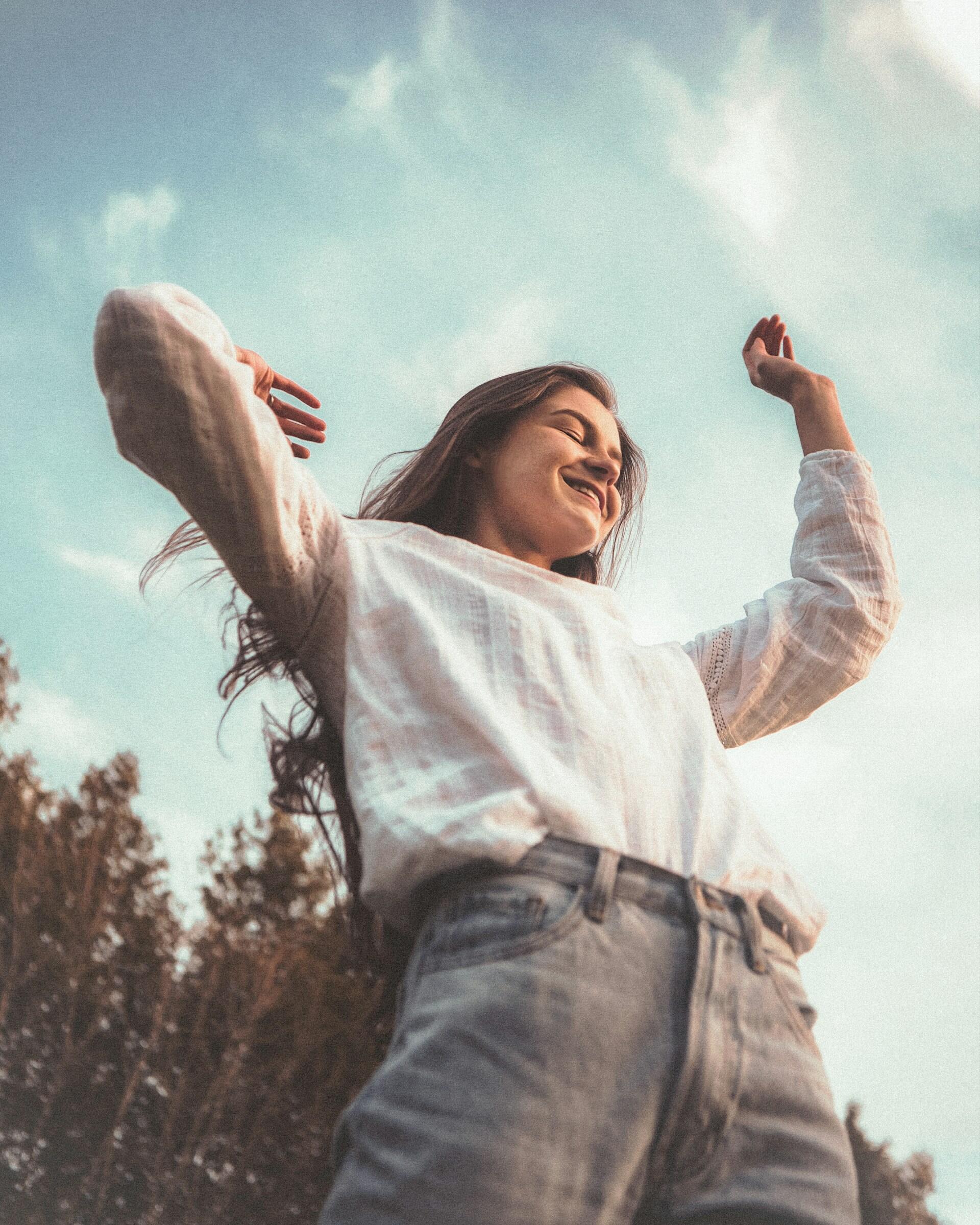 Una ragazza solleva le braccia sorridendo in un gesto che comunica relax e soddisfazione.