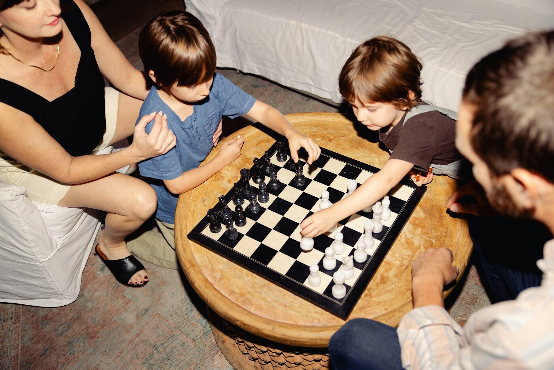 Genitori insegnano ai figli e giocare a scacchi.
