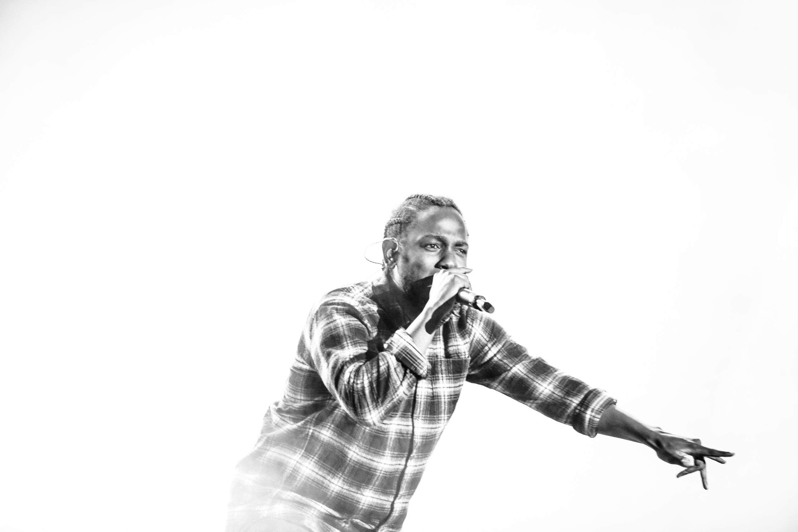 Un'immagine in bianco e nero di Kendrick Lamar durante un concerto. 