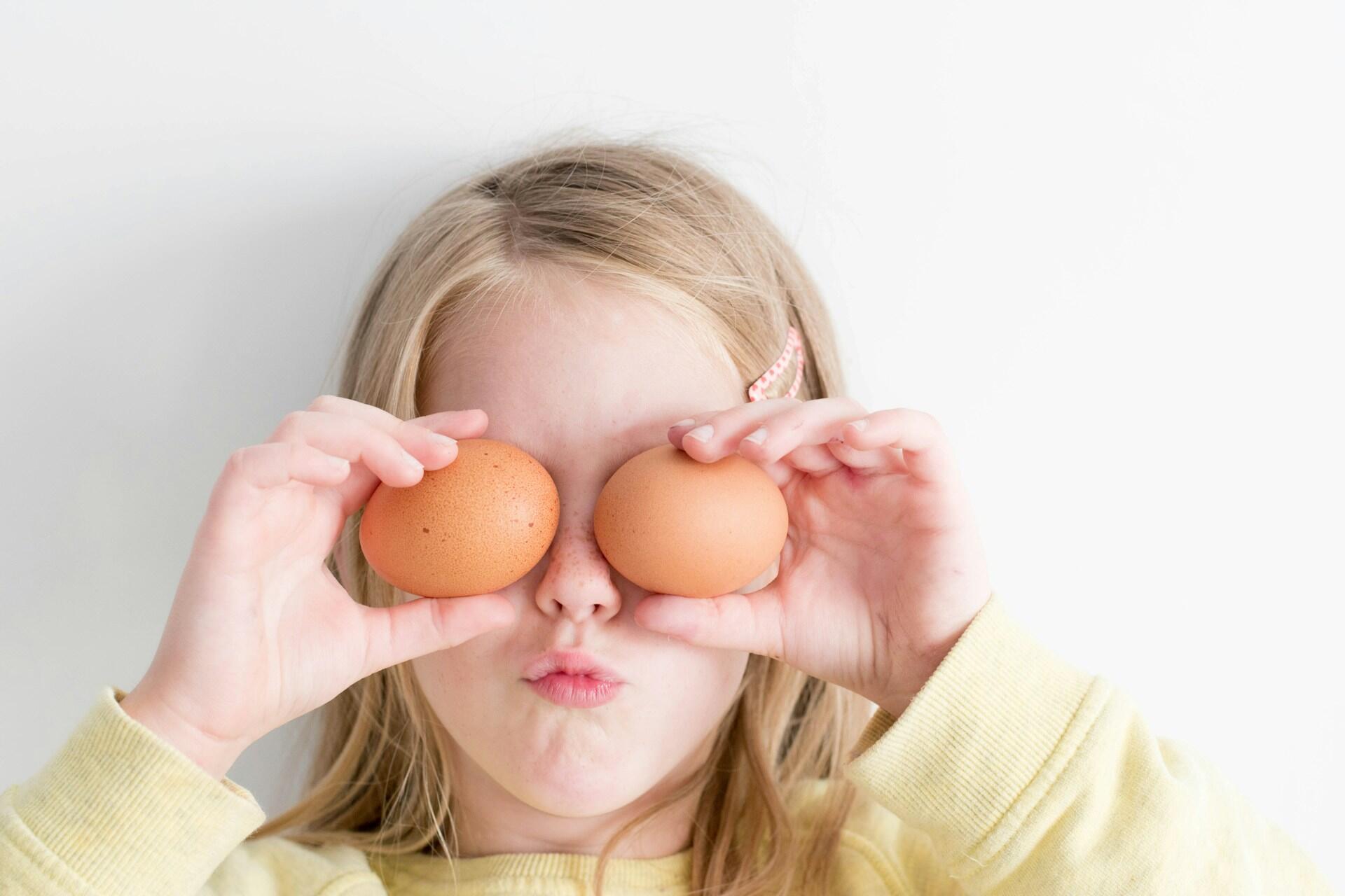 Bambina che si tiene due uova sugli occhi