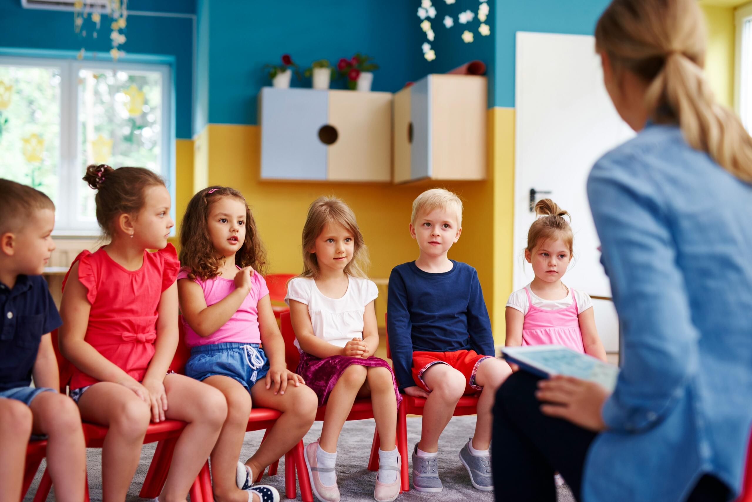Gruppo di bambini in classe davanti ad una maestra.