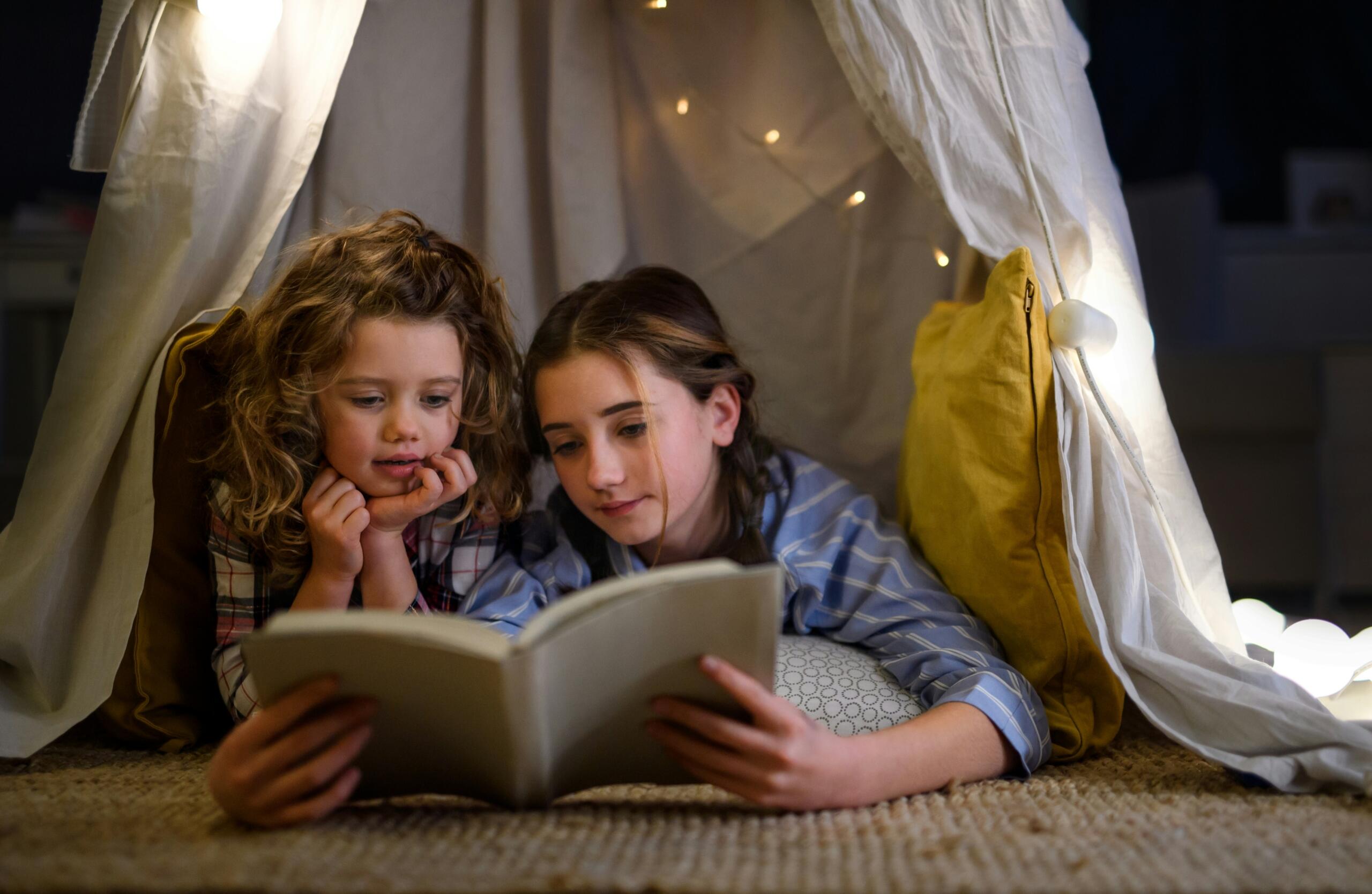 Due bambine leggono un libro in camera da letto.
