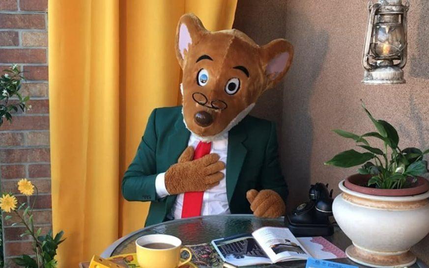 Geronimo Stilton seduto ad un tavolo con una tazza di caffè