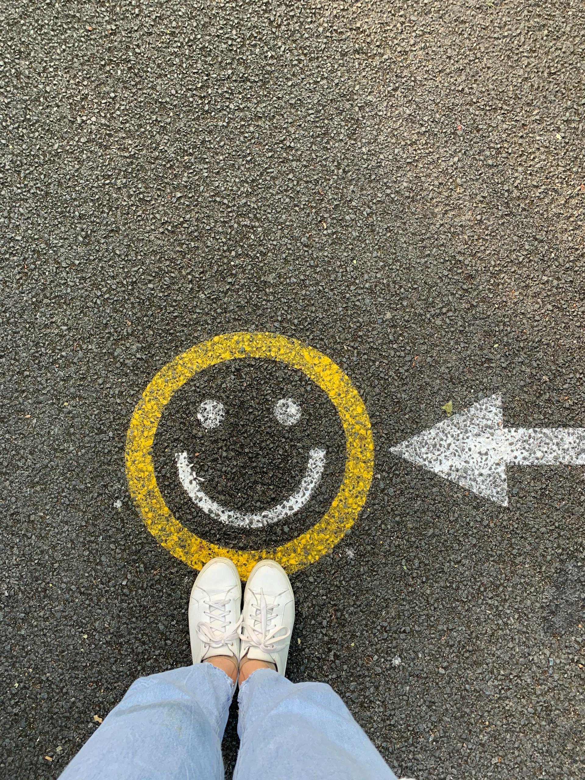 Ripresa dall'alto di uno smiley disegnato sulla strada e piedi di una ragazza