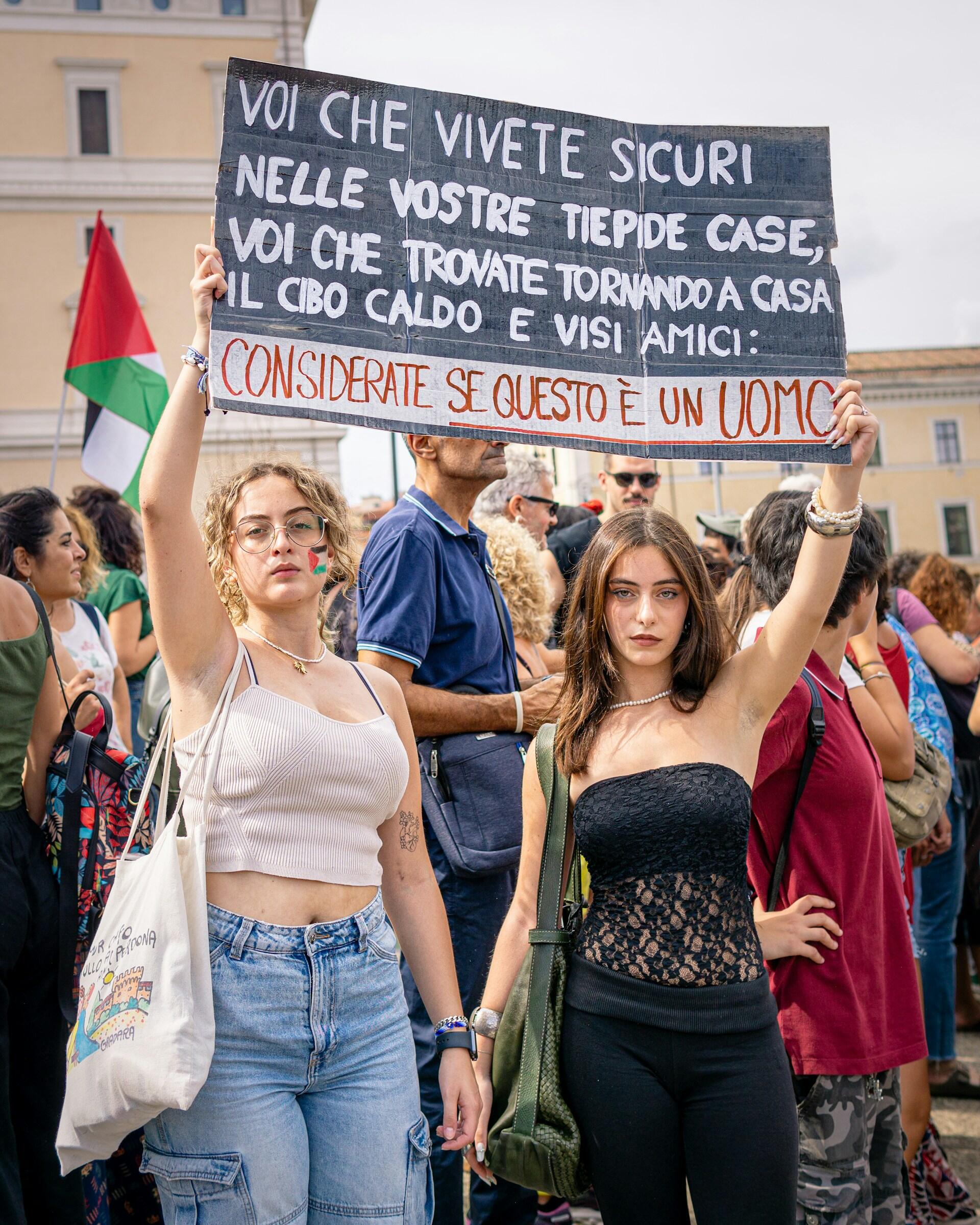 Ragazze tengono in mano un cartello con una citazione di Primo Levi durante una manifestazione. Foto di Leonardo Basso. 