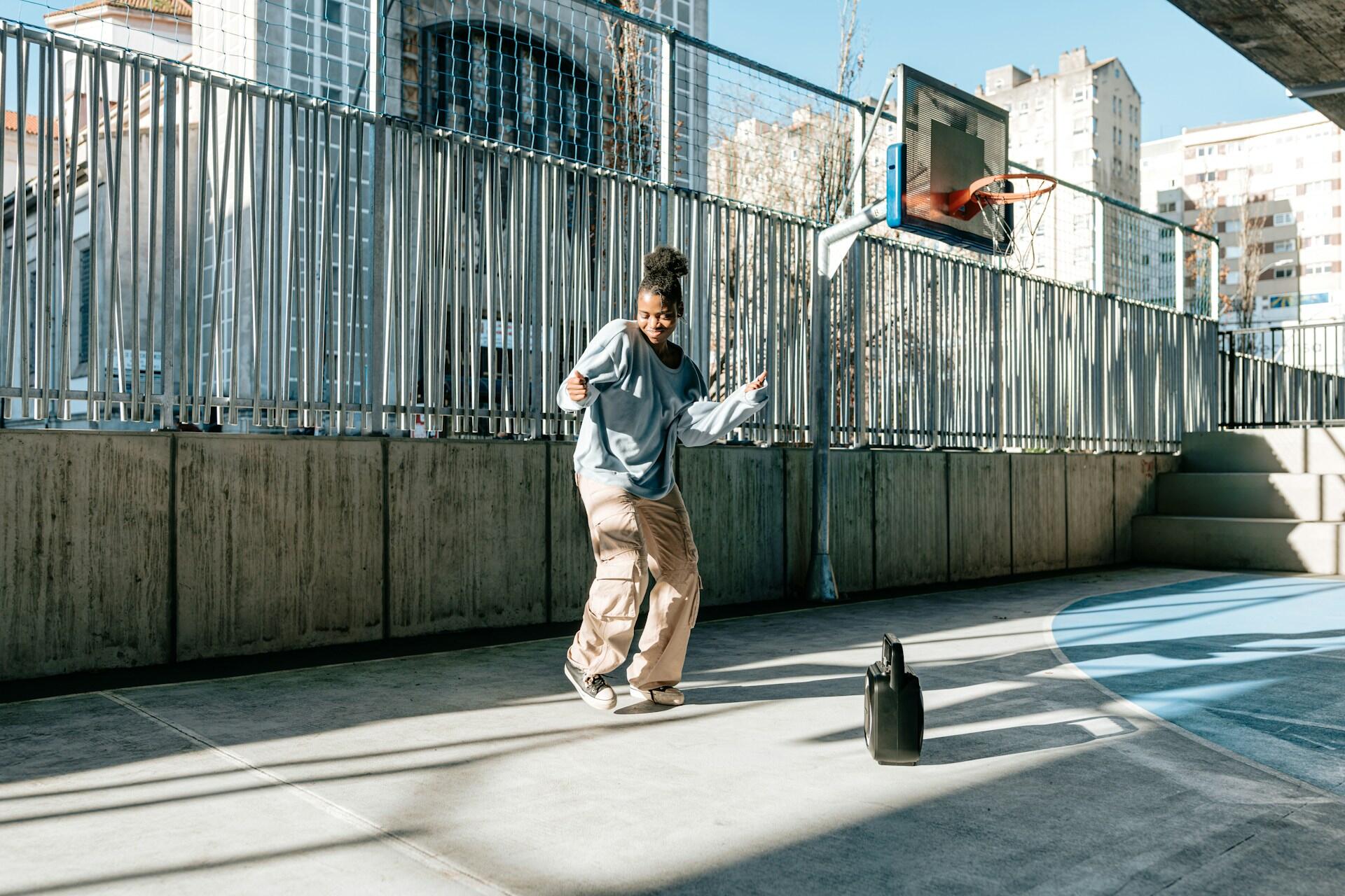 Ragazza balla musica hip hop in un campo da basket. 