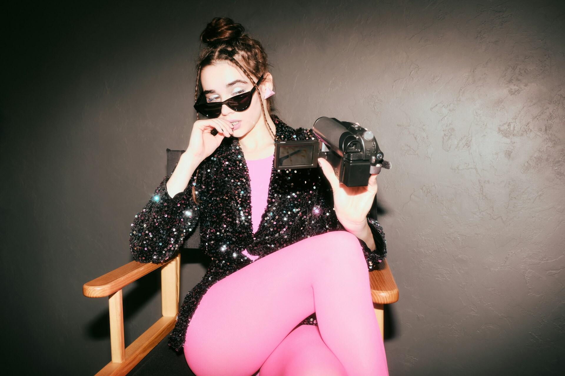 Una cantante pop posa con una videocamera in mano.