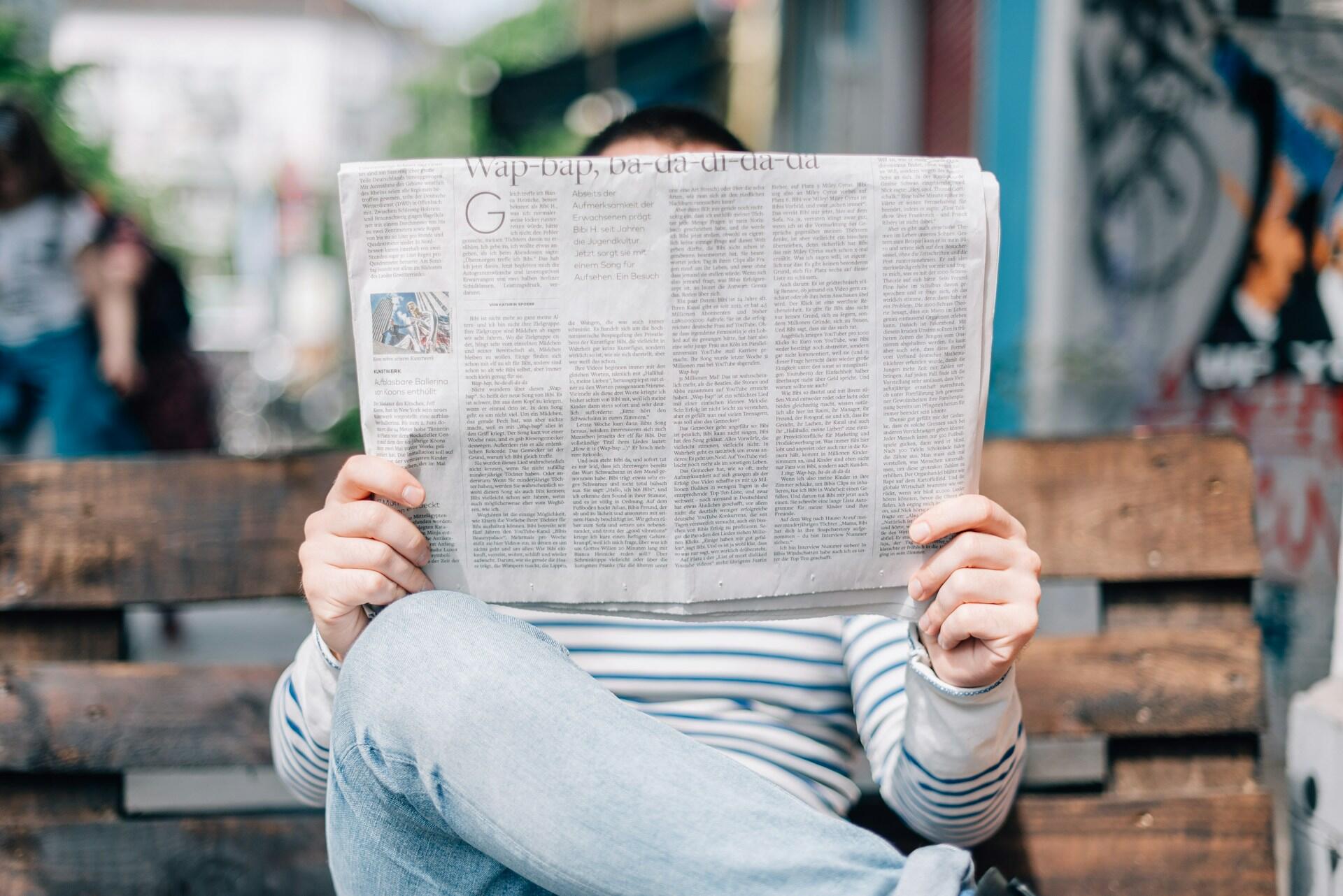 Ragazzo che legge il giornale sulla panchina