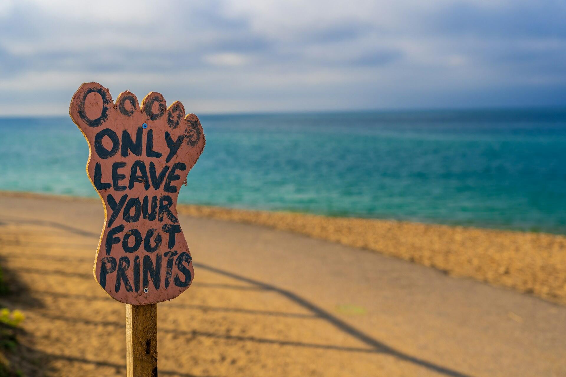 Immagino con cartello a forma di impronta sulla spiaggia