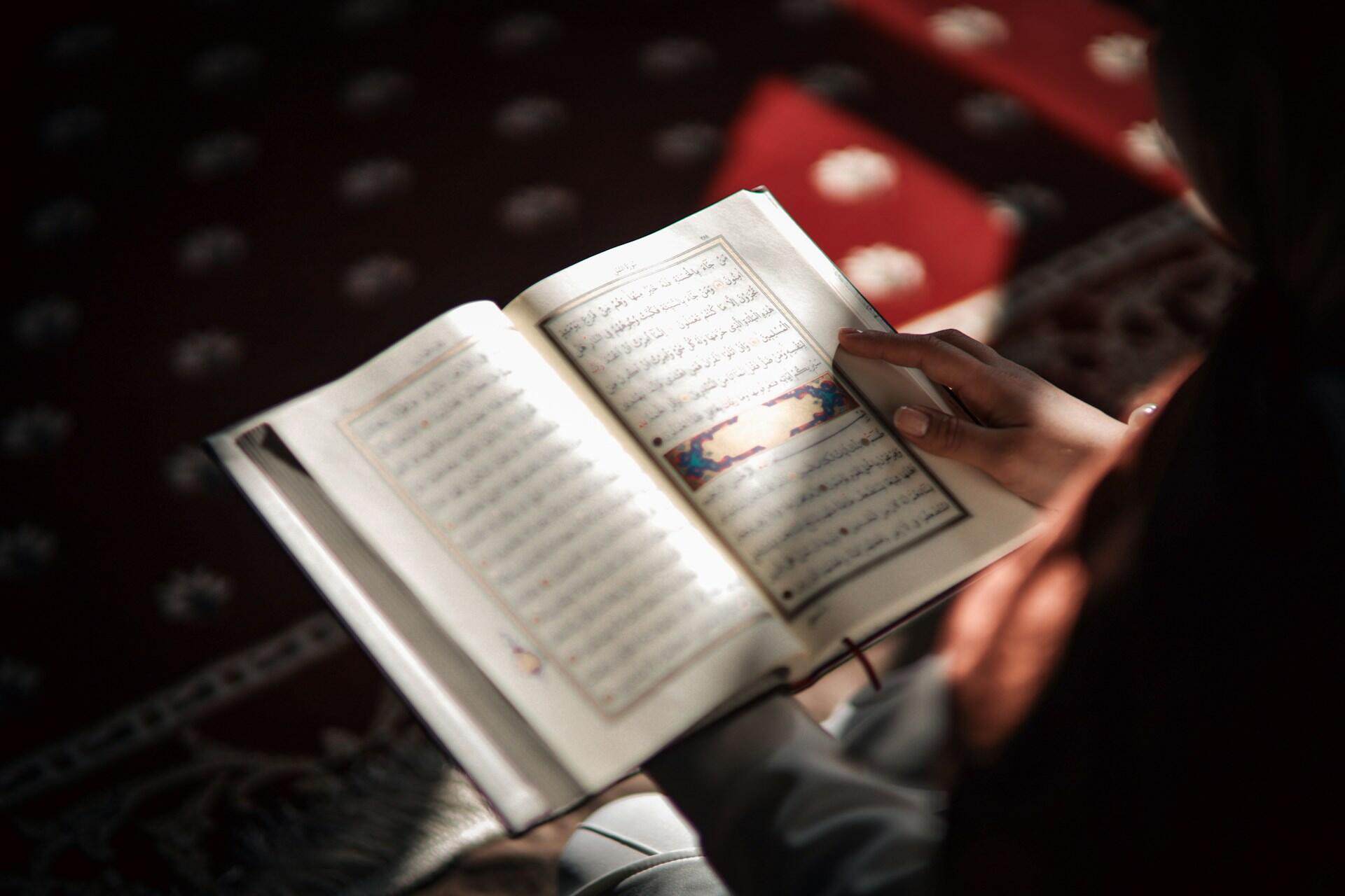 Ragazza legge un libro scritto con l'alfabeto arabo.