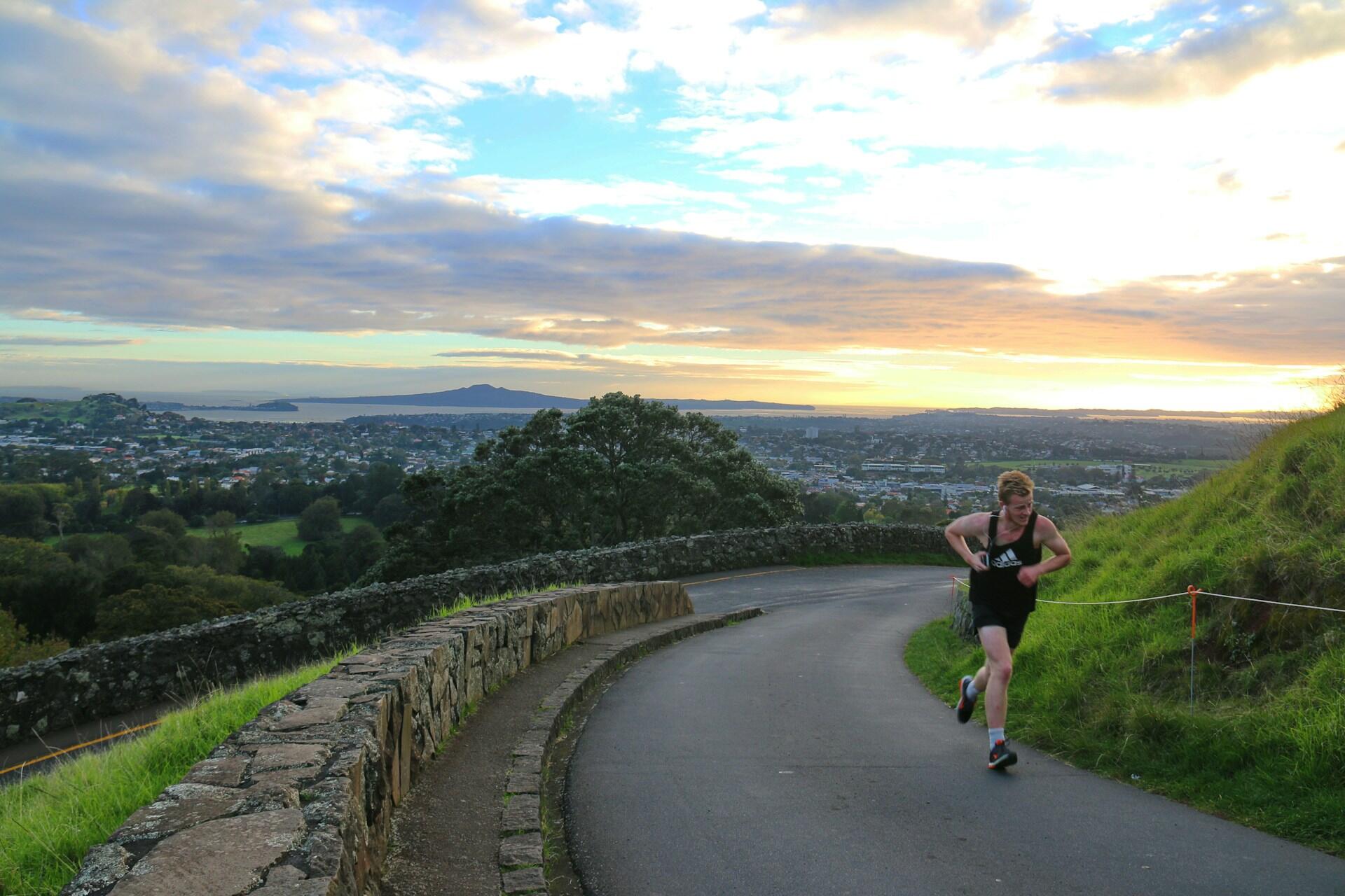Runner corre su una collina con un panorama al tramonto.