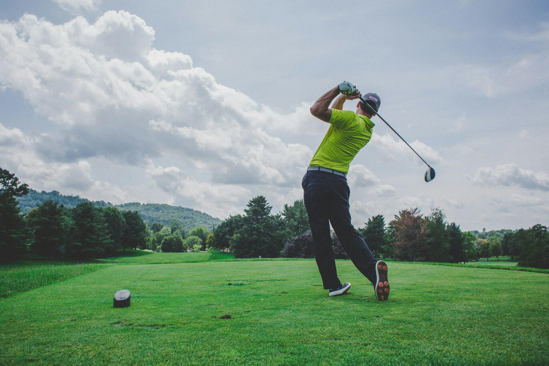 Un uomo con una mazza da golf lancia una pallina in un campo da gioco.