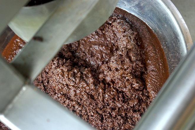 Mixer contenente la pasta di cacao macinato, passaggio essenziale per la preparazione del cioccolato.