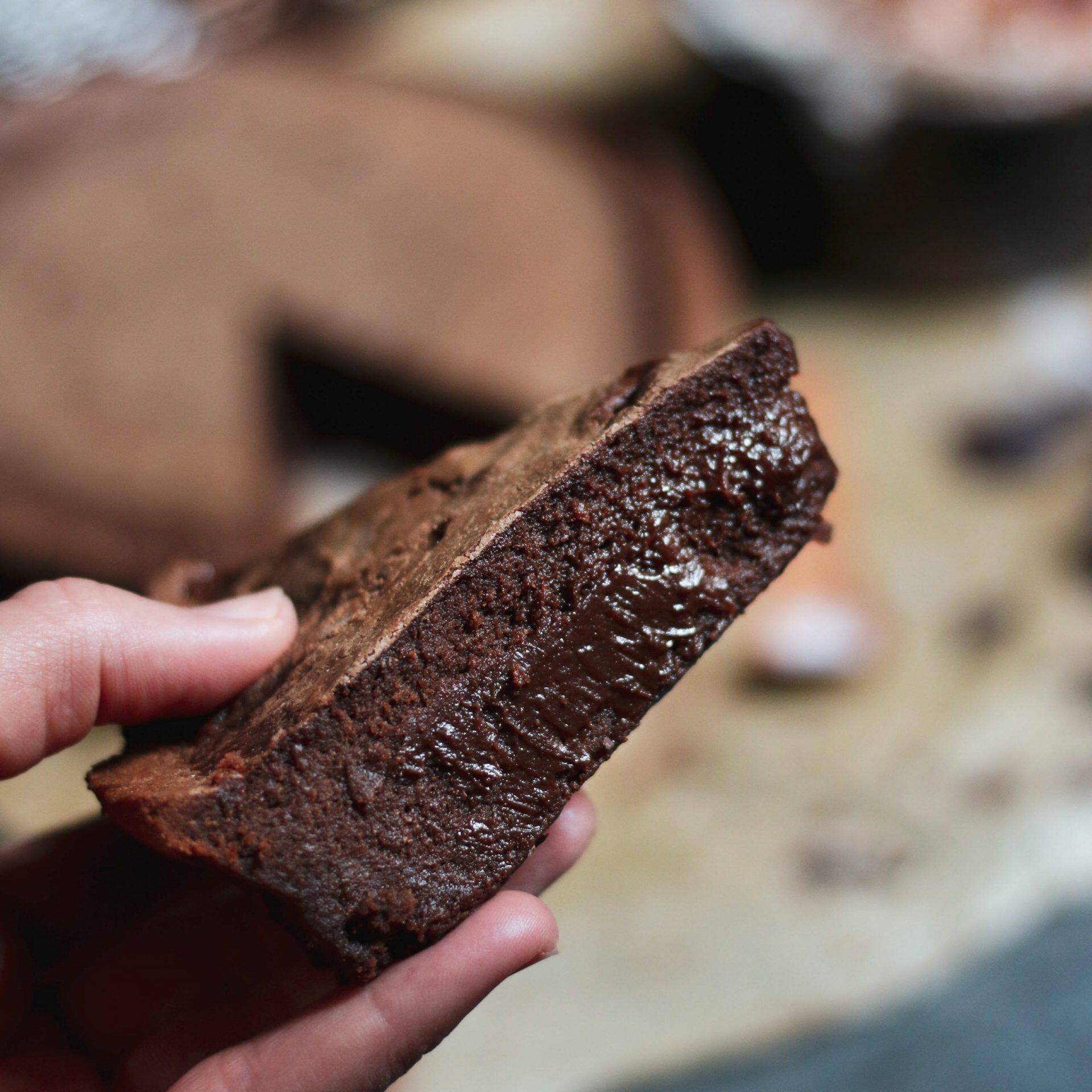 Mano che tiene una fetta di torta al cioccolato fatta in casa.