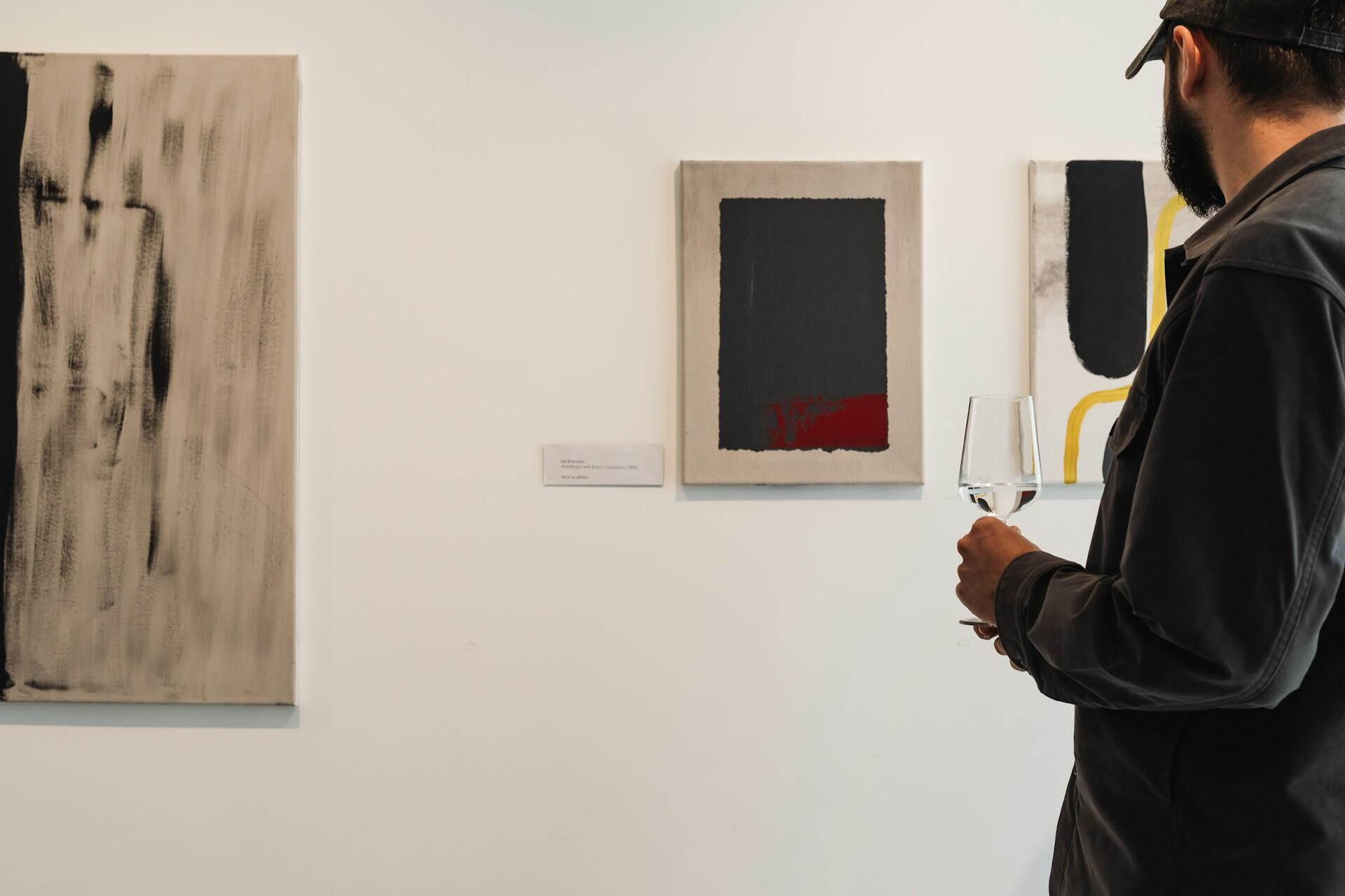 Un ragazzo ammira un quadro in una fiera d'arte durante un vernissage. 